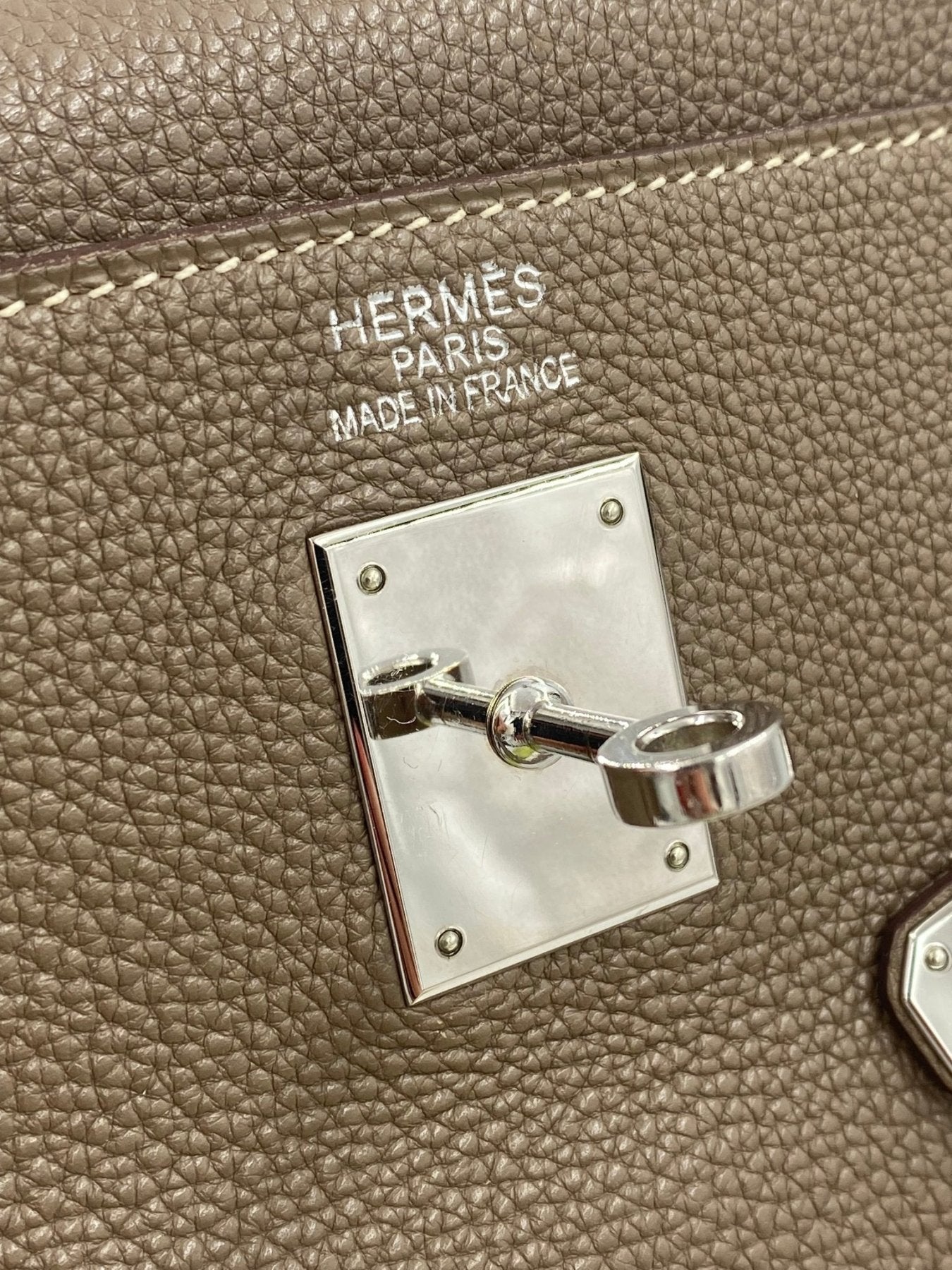 HERMES Kelly 35 Togo Etoupe Detailaufnahme des Palladium-Verschlusses und Markenpraegung auf genarbtem Togoleder