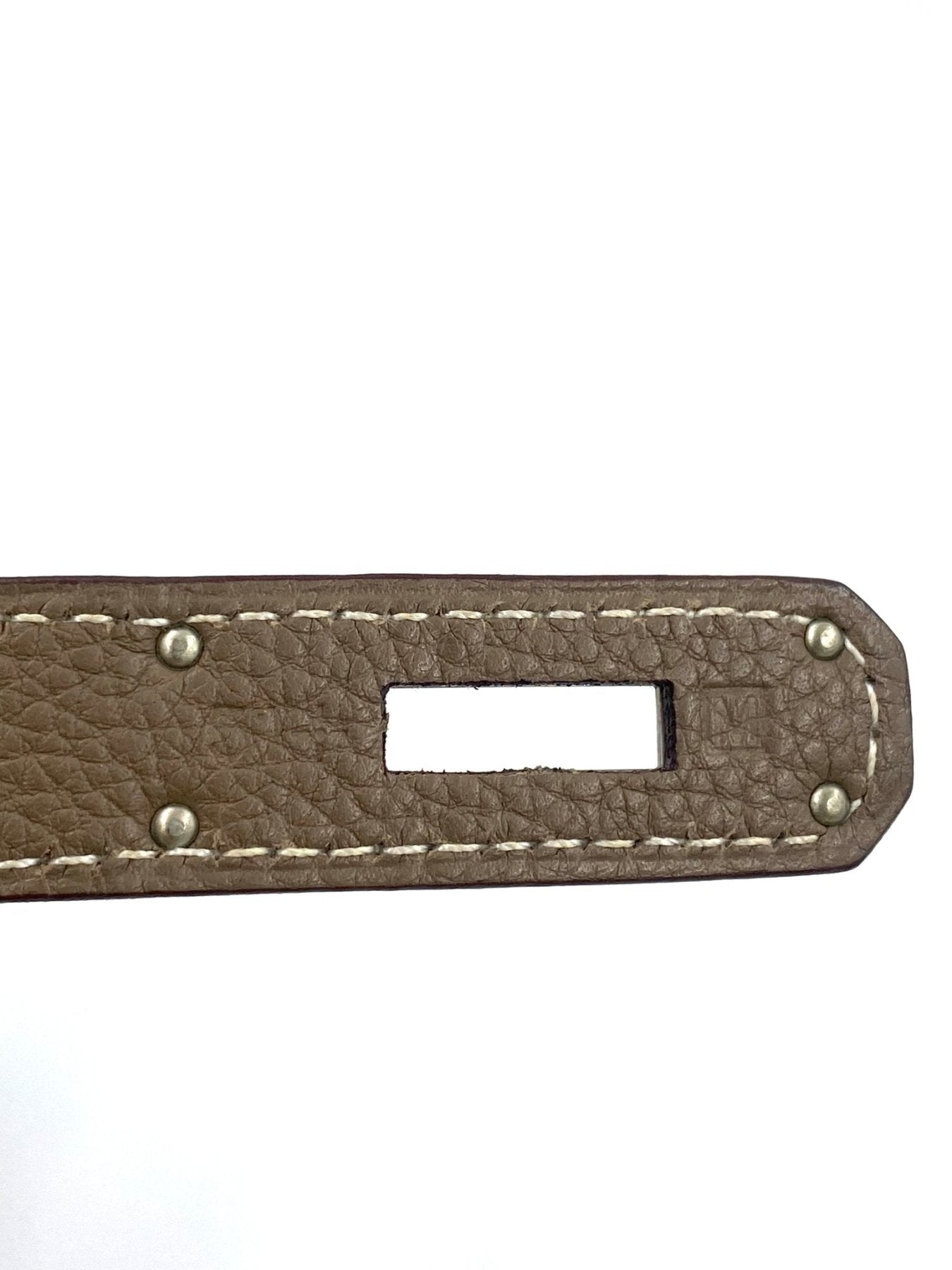 Nahaufnahme eines Hermes Kelly Taschengriffs aus Togoleder in Etoupe mit weisser Kontrastnaht und Palladium-Details
