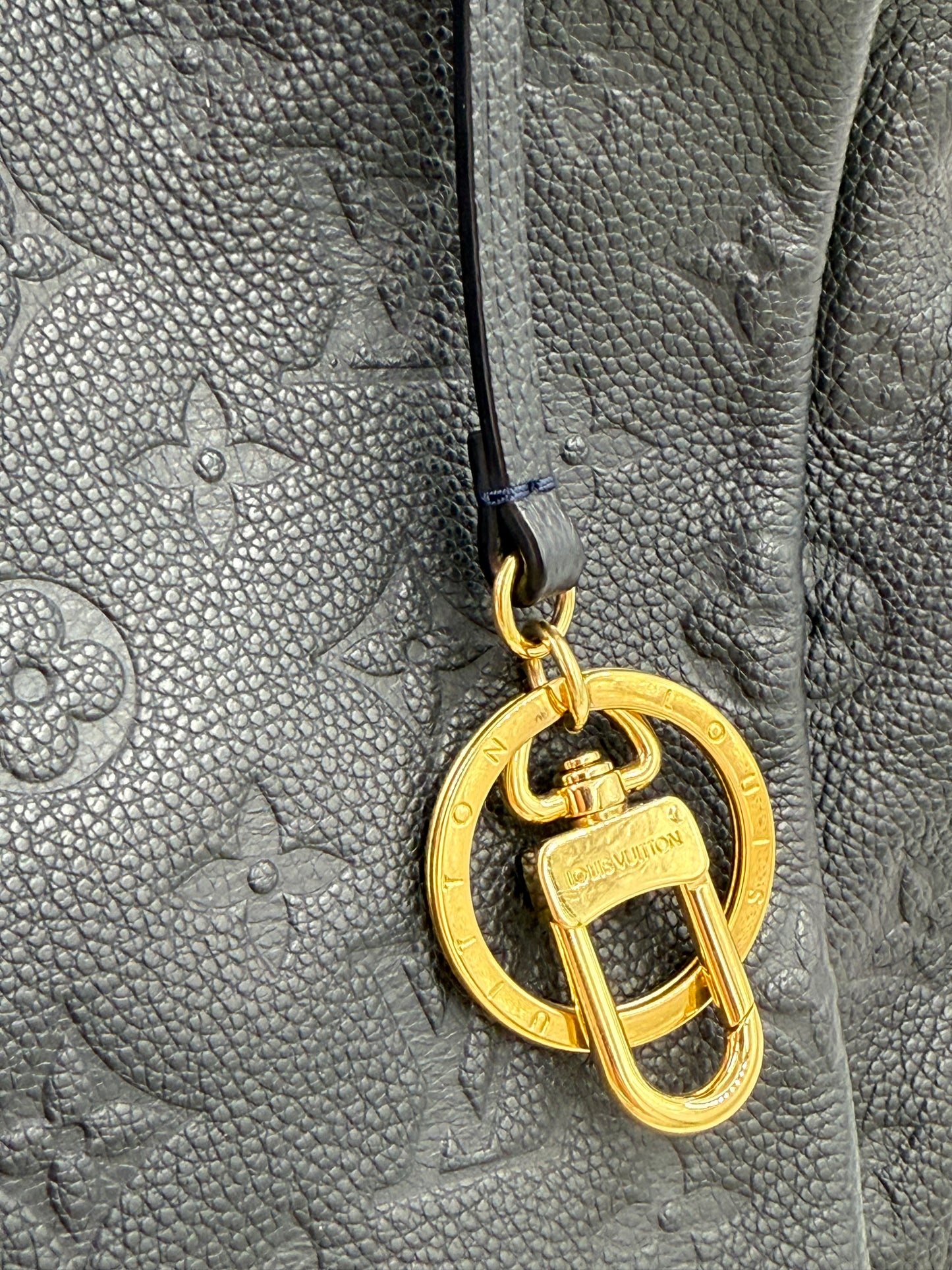 LOUIS VUITTON Artsy MM Monogram Empreinte Infini Tasche aus geprägtem Leder mit goldfarbenem Schlüsselanhänger.