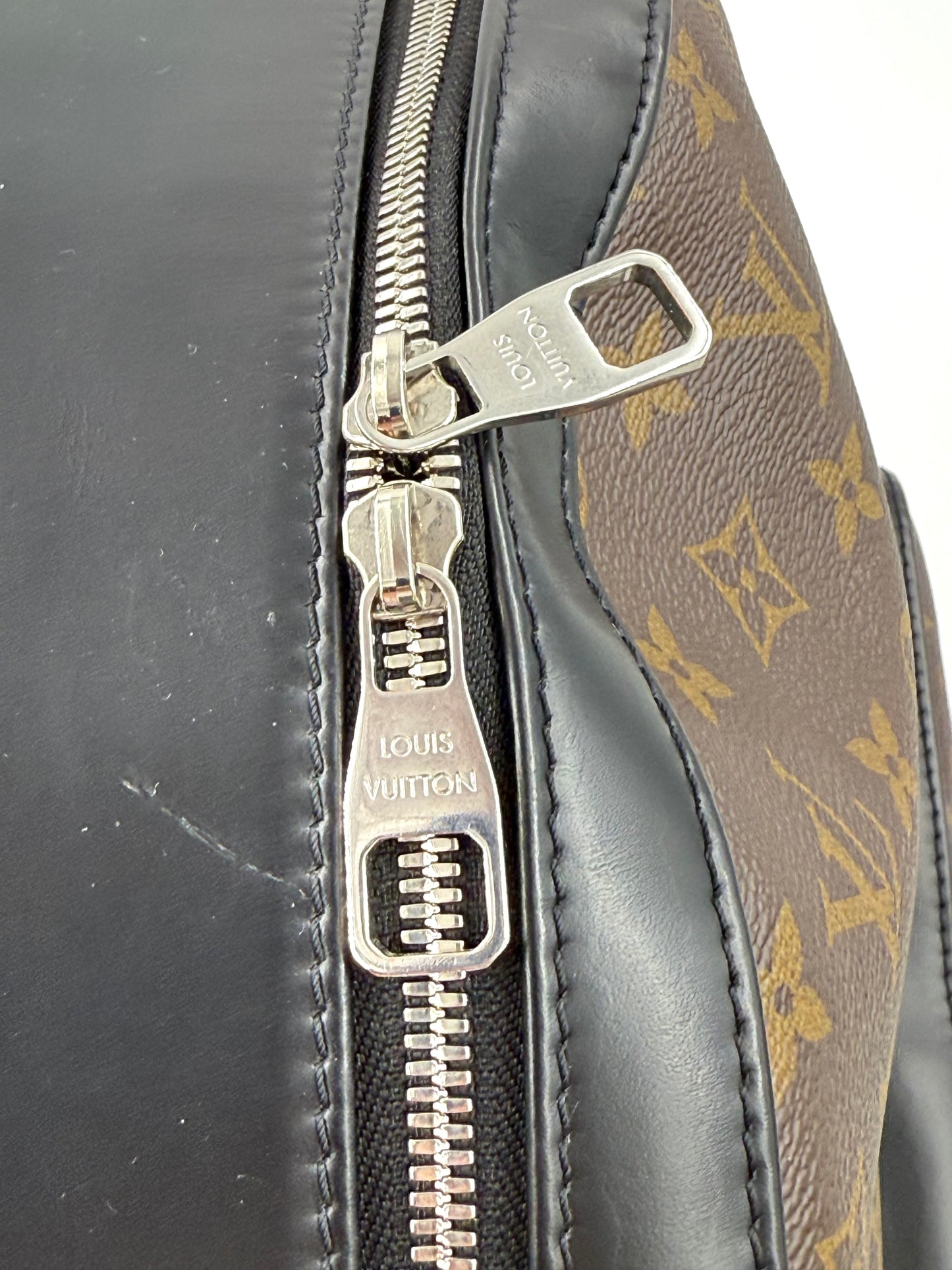 Detailaufnahme des Reißverschlusses der LOUIS VUITTON Josh Monogram Canvas Tasche in braunem Monogramm und schwarzem Leder.