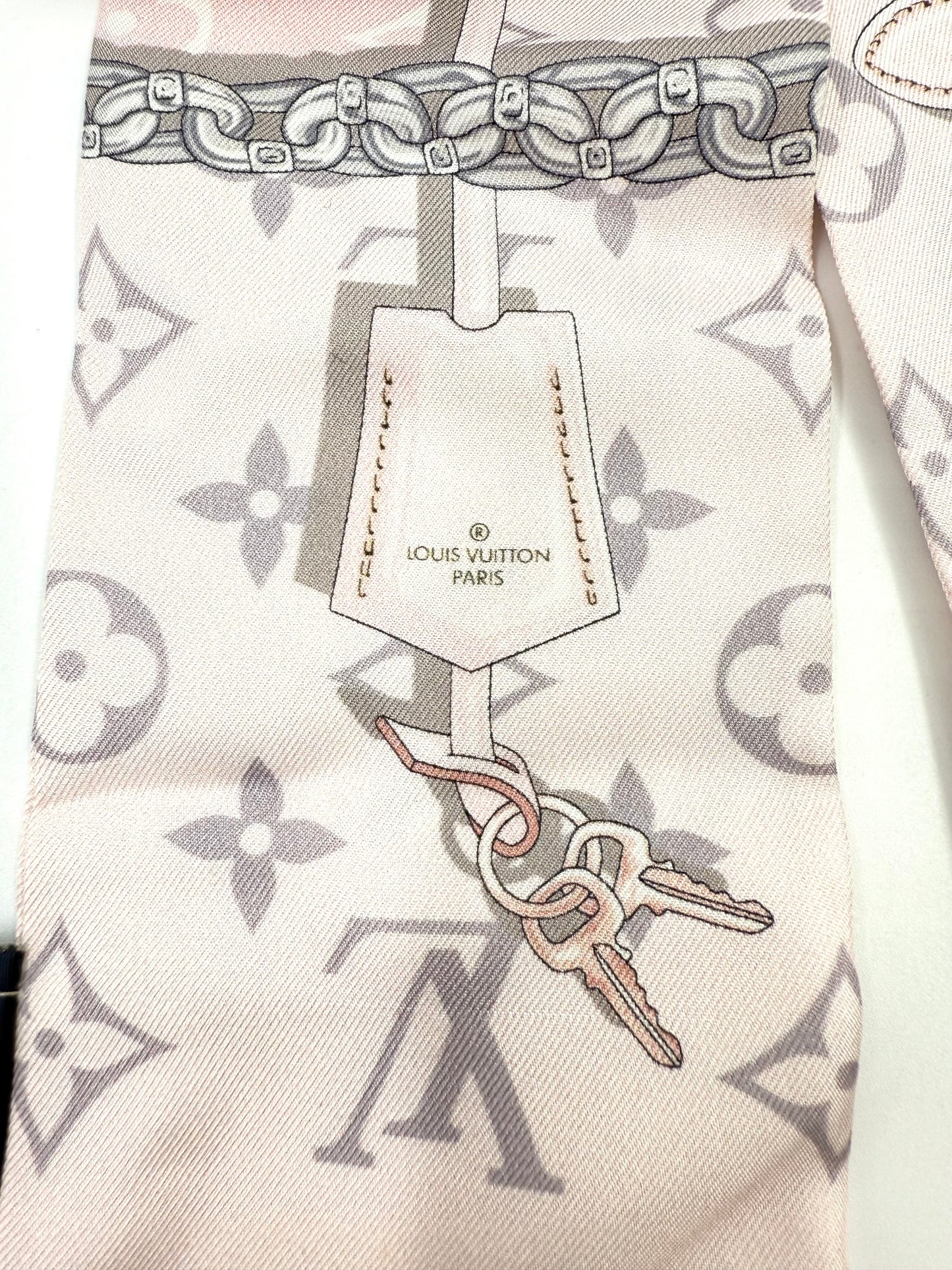 LOUIS VUITTON Bandeau Rose Ballerine mit Schlüsselanhänger-Design und zartem Monogramm-Muster in Pastellfarben.
