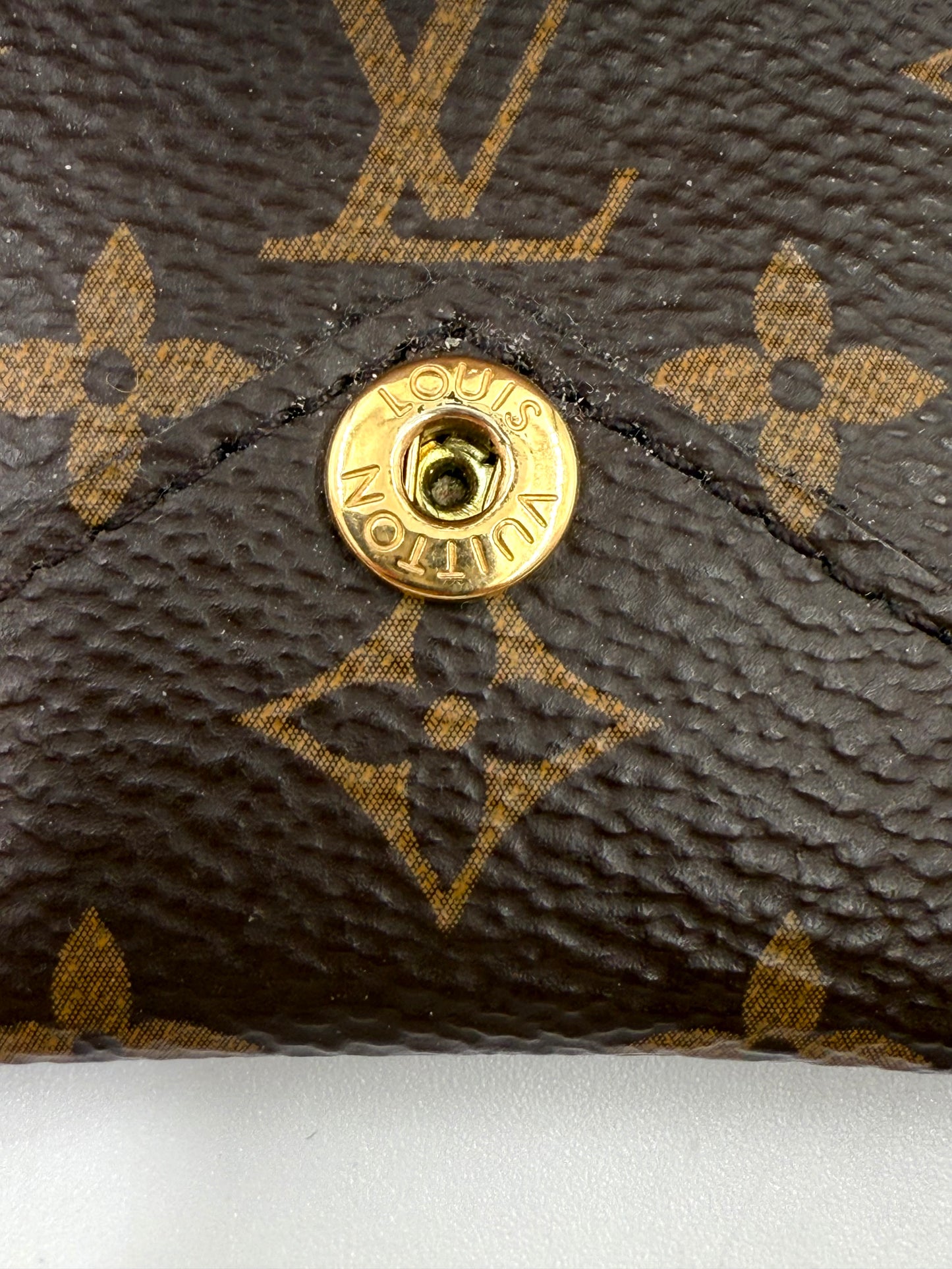 LOUIS VUITTON Kirigami Pouch Monogram Canvas Detailaufnahme des goldenen Druckknopfs und des Monogramm-Canvas-Musters.