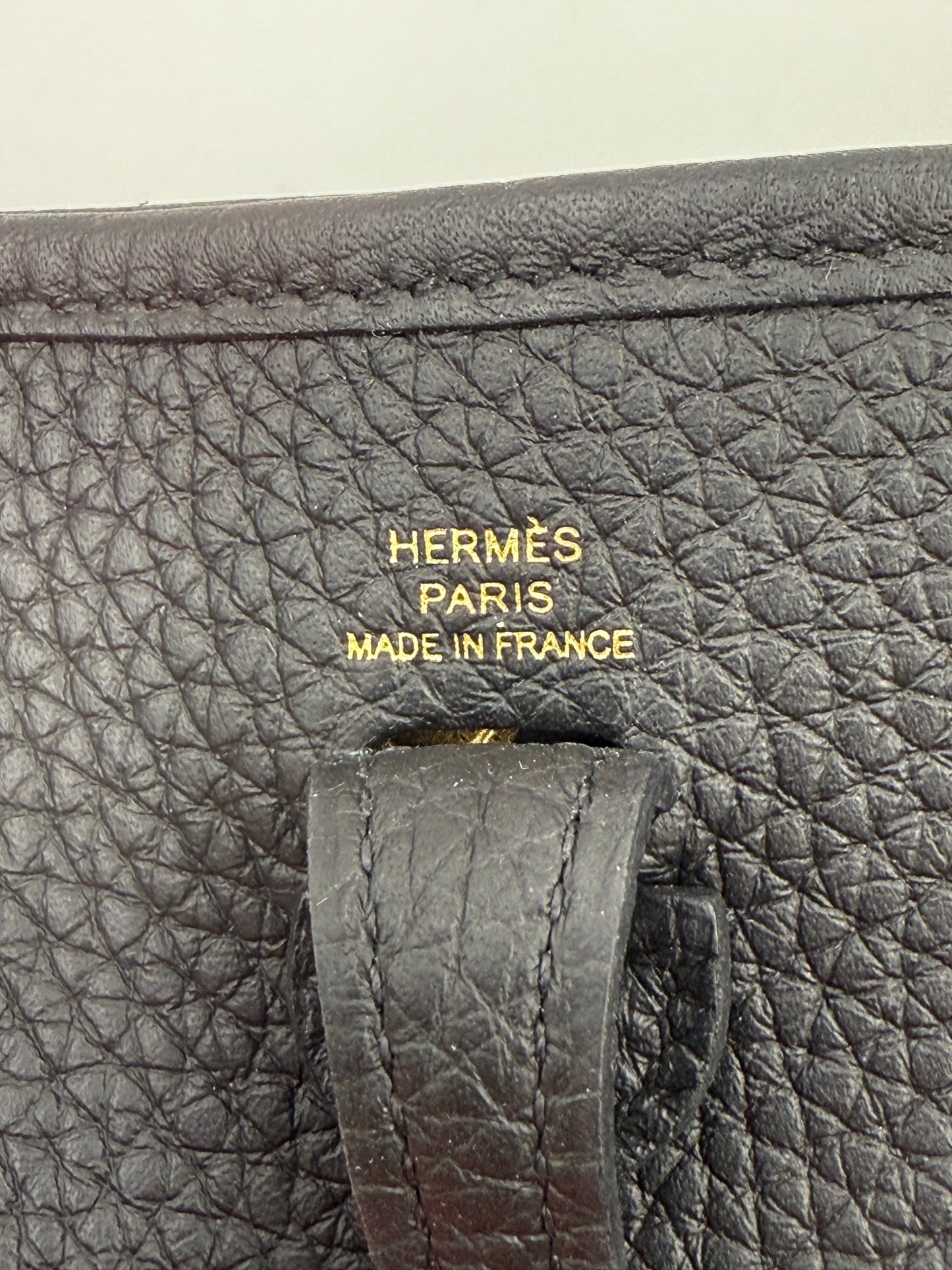 HERMÈS Evelyne 16 Taurillon Clemence schwarz GHW Detailaufnahme des geprägten Leders und goldenen Logos.