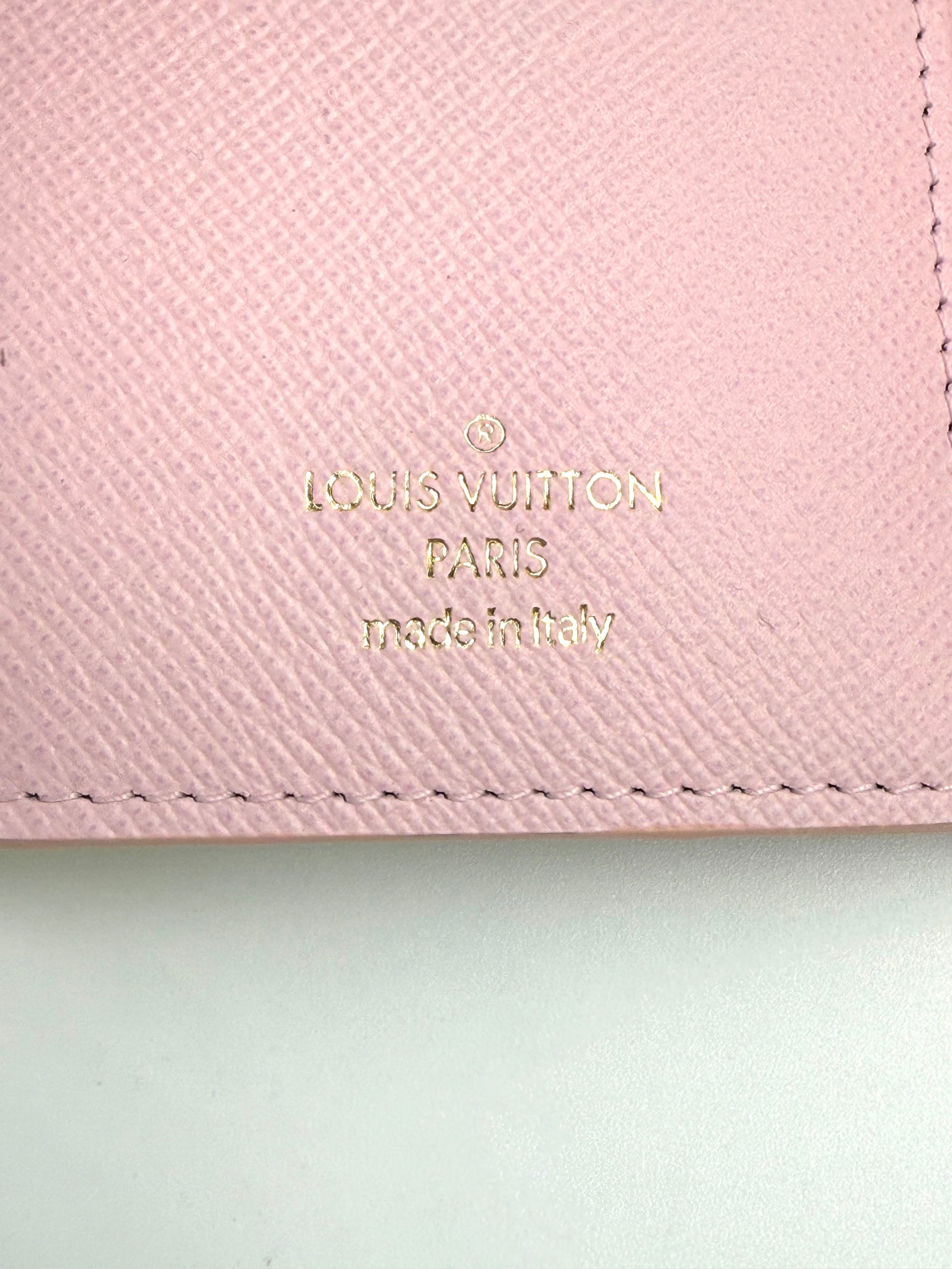 LOUIS VUITTON Victorine Wallet „By the Pool“ Nahaufnahme des goldenen Markenlogos auf rosa Leder, made in Italy.