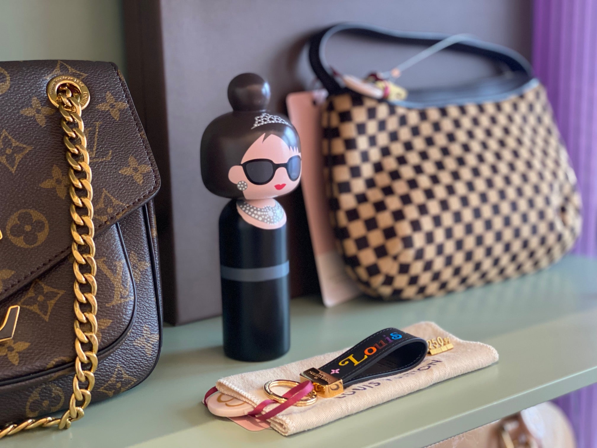Holzfigur Audrey Hepburn im Regal neben Designer Taschen