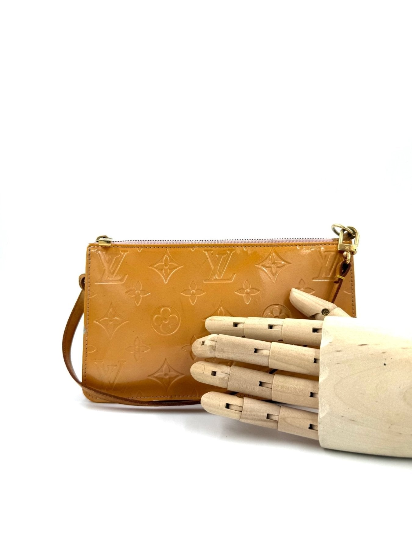 Louis Vuitton Pochette Lexington in gelbem Monogram Vernis Lackleder mit goldfarbenen Details, neben Holzhand fotografiert