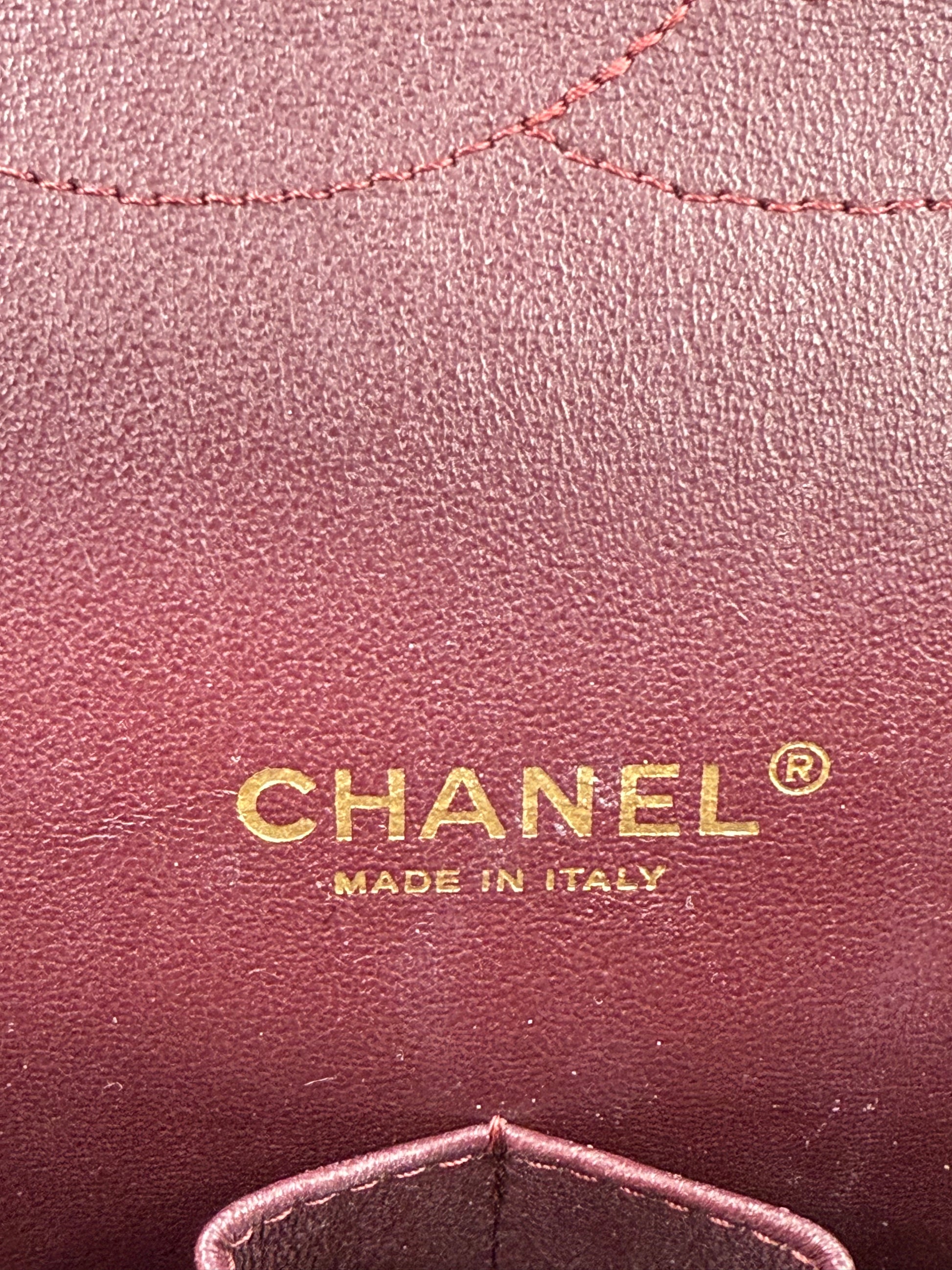 CHANEL Timeless Double Flap Maxi Caviar Logo und Prägung „Made in Italy“ auf rotem Innenleder.