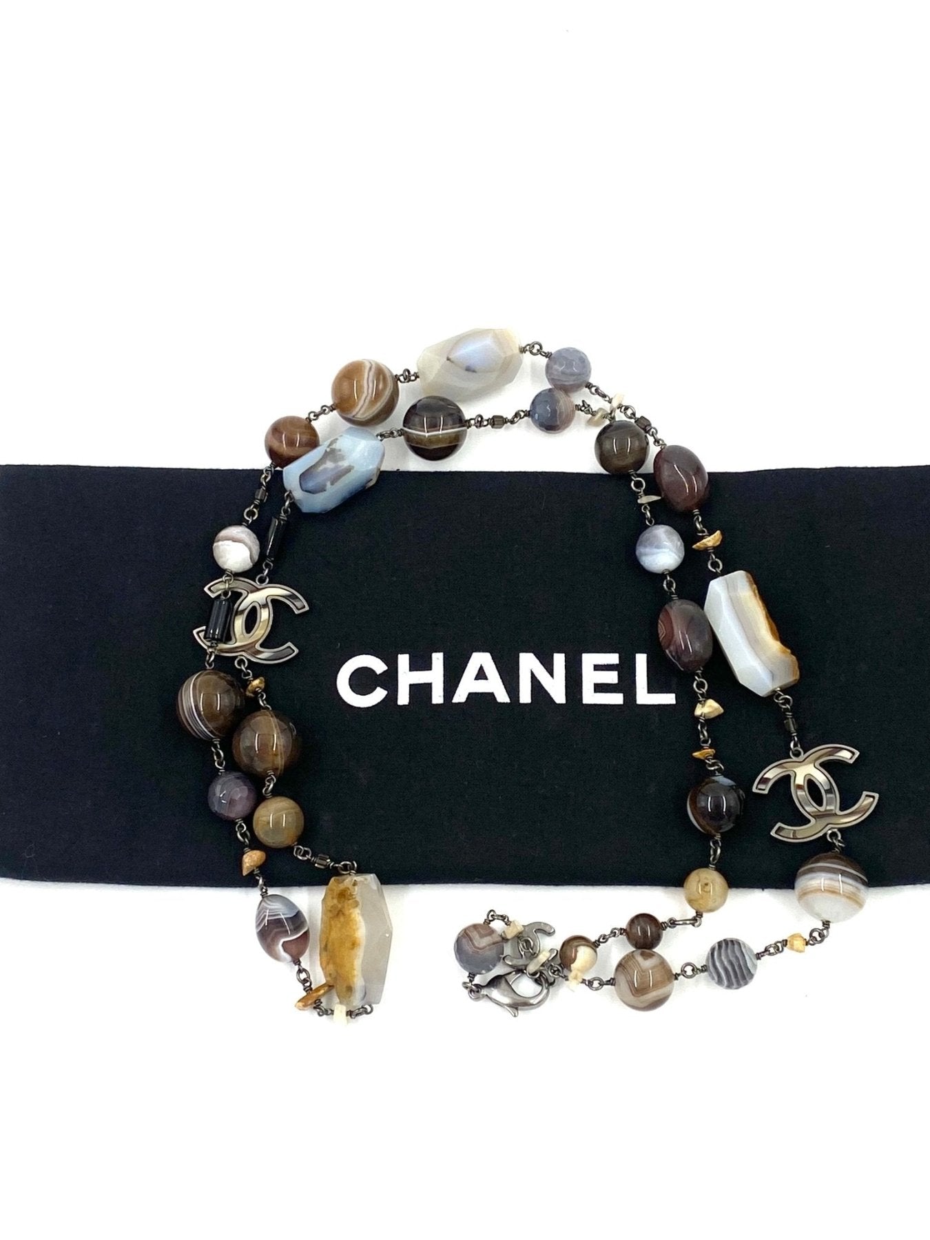 CHANEL lange Halskette CC mit mehrfarbigen Natursteinen und CC-Logo Anhaengern auf schwarzem Hintergrund