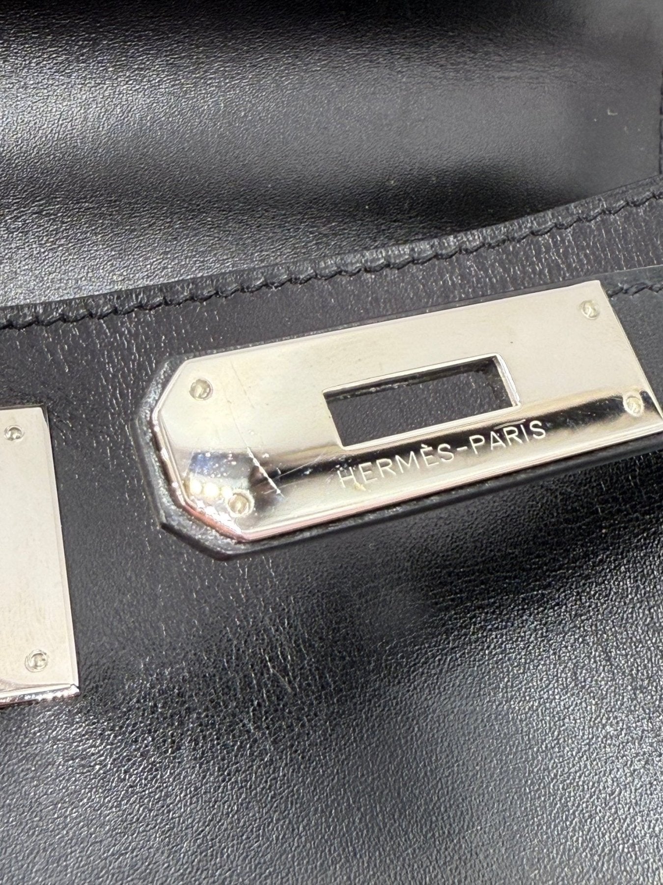 HERMES Kelly 28 Boxleder schwarz Vintage - Nahaufnahme der Palladium-Verschlussplatte auf schwarzem Glattleder