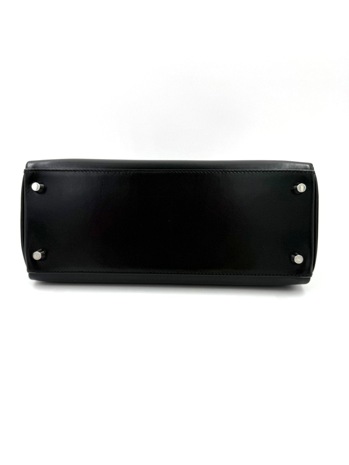 HERMES Kelly 28 Boxleder schwarz Vintage Tasche Bodenansicht mit vier silbernen Metallfuessen auf schwarzem Leder
