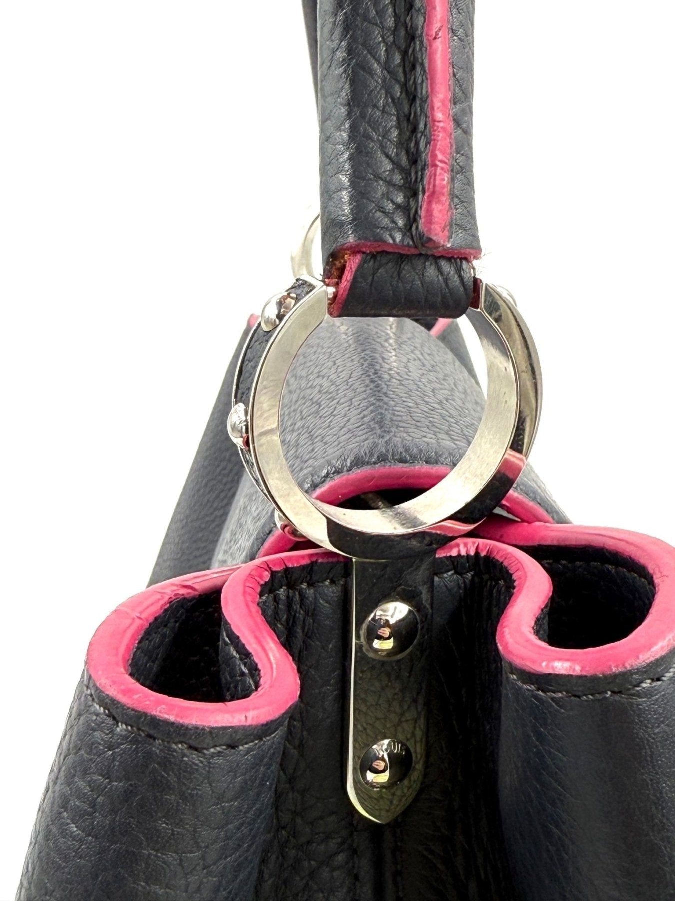 Detailaufnahme der Louis Vuitton Capucines MM Tasche mit Henkelring und rosa Lederdetails in schwarzem Taurillon Leder