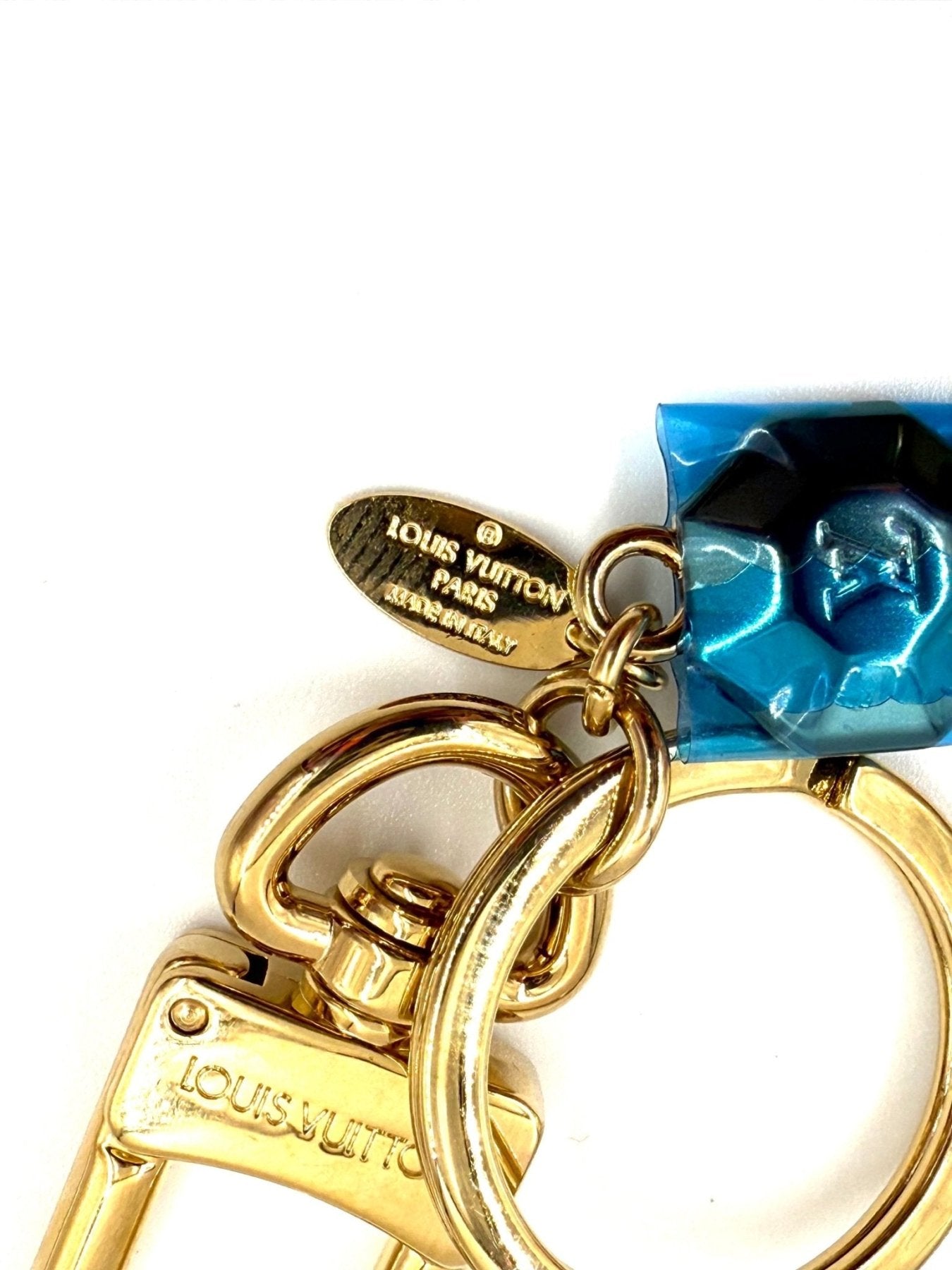 Louis Vuitton Facettes Schluesselanhaenger in Gold mit blauer Kristallverzierung und markentypischem Anhaenger