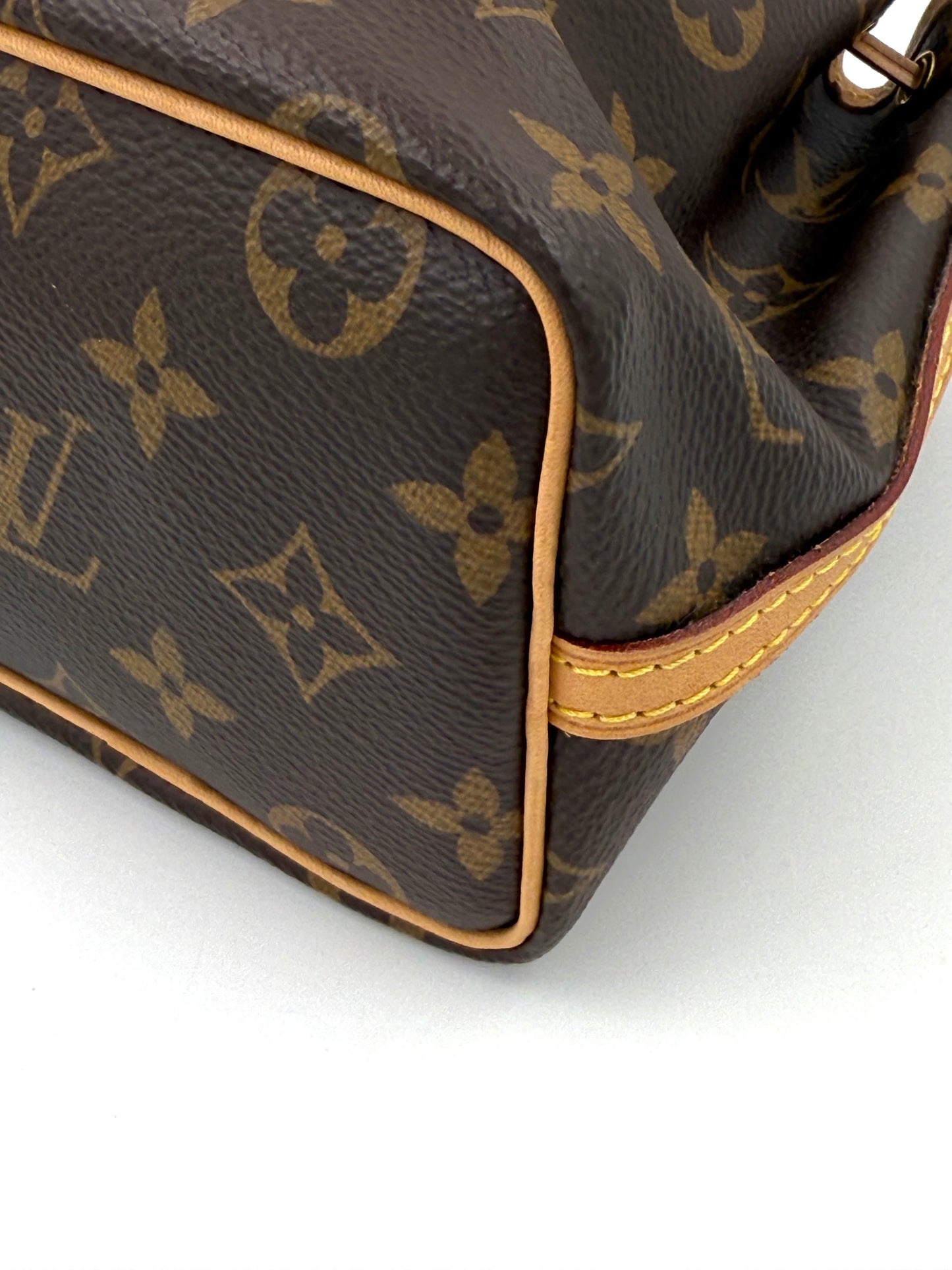 Detailaufnahme der Louis Vuitton Nano Noe Monogram Canvas Tasche mit sichtbaren Nähten und Lederbesatz.