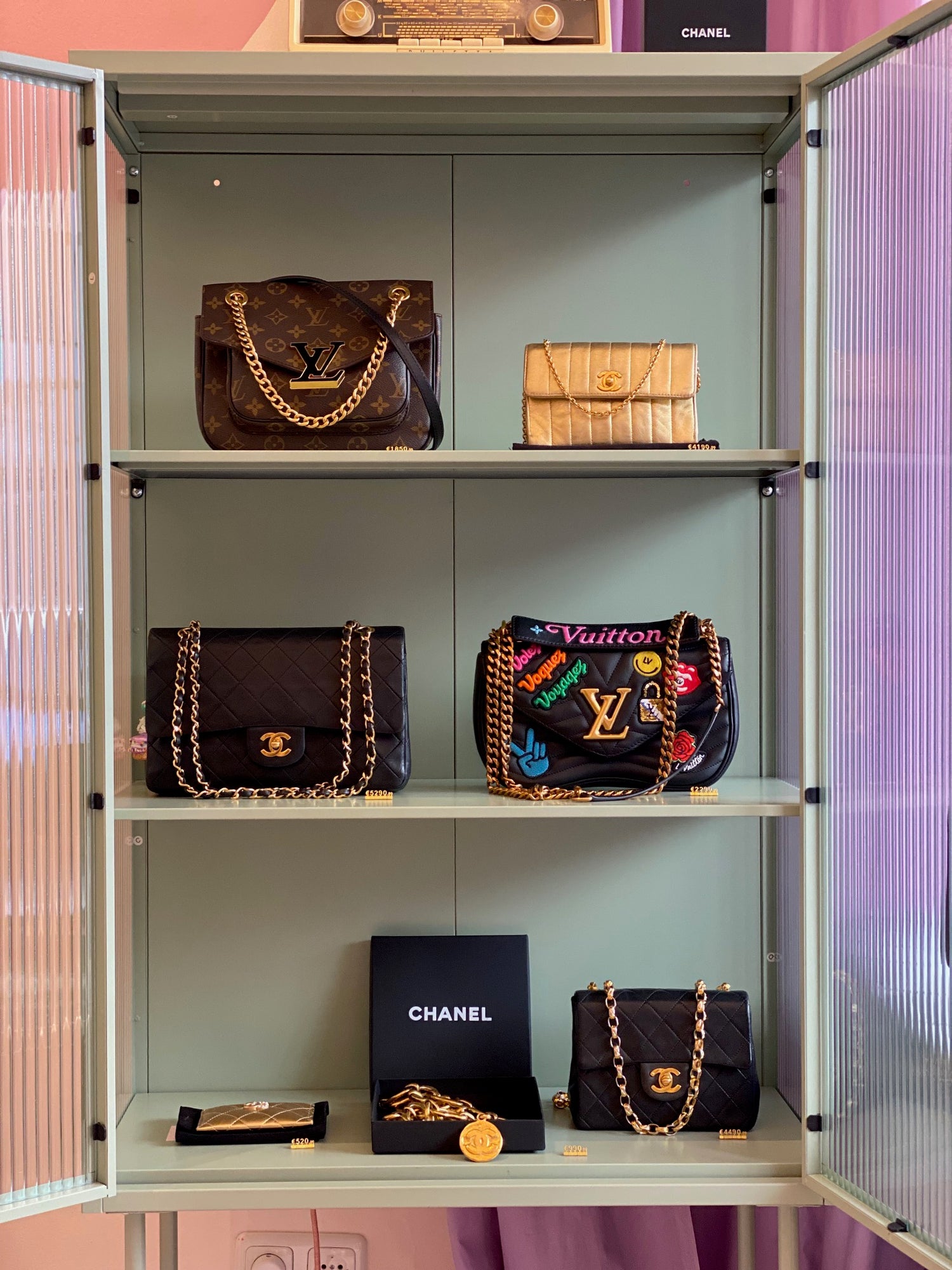Mehrere Designerhandtaschen von Louis Vuitton und Chanel stehen in einer Vitrine zur Präsentation