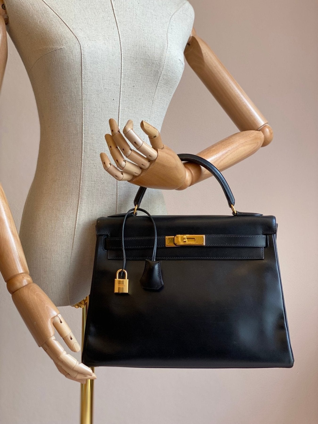 HERMES Kelly 32 Handtasche aus schwarzem Boxkalbsleder mit goldfarbenen Beschlagen auf Schaufensterpuppe prasentiert