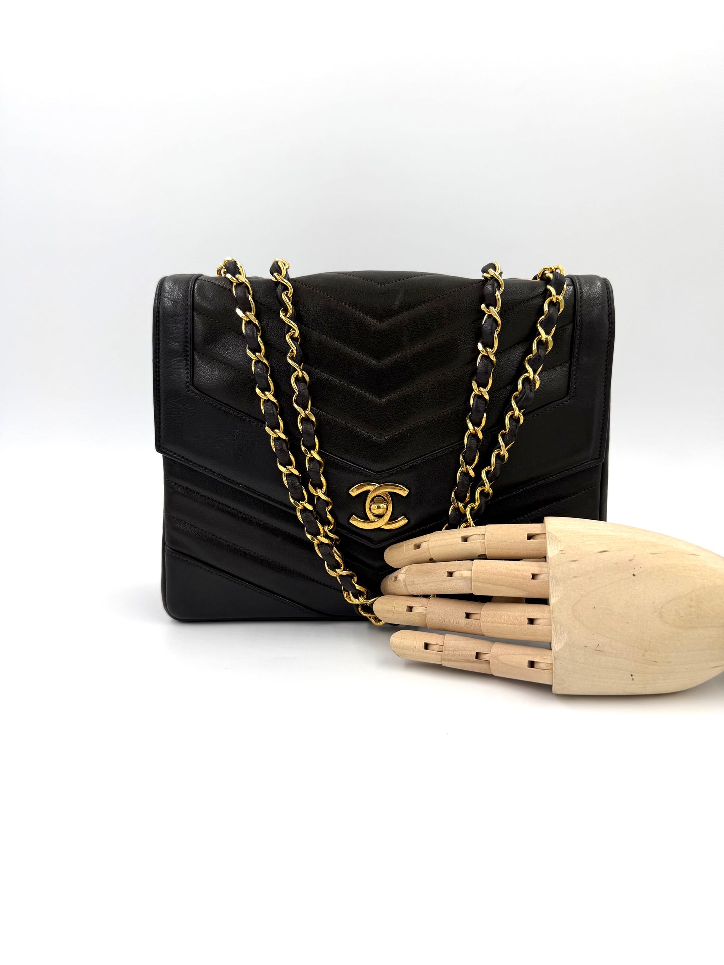 CHANEL Single Flap Lammleder schwarz GHW Handtasche mit gestepptem Chevron-Muster und goldfarbenem Kettenriemen vor weißem Hintergrund
