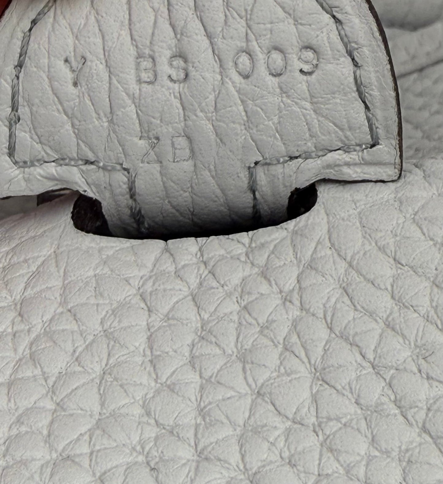 Nahaufnahme der Seriennummer und Ledertextur der HERMÈS Evelyne 29 Tasche in Bleu Pale mit goldfarbener Hardware
