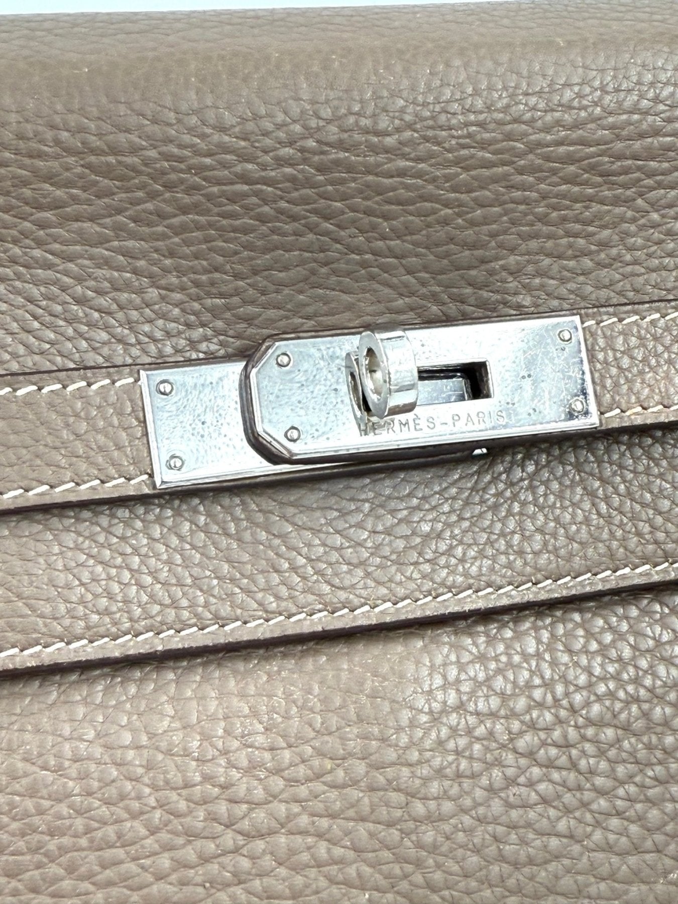 Nahaufnahme des silbernen Drehverschlusses einer HERMES Kelly 35 Tasche in Etoupe mit charakteristischer Lederkornstruktur