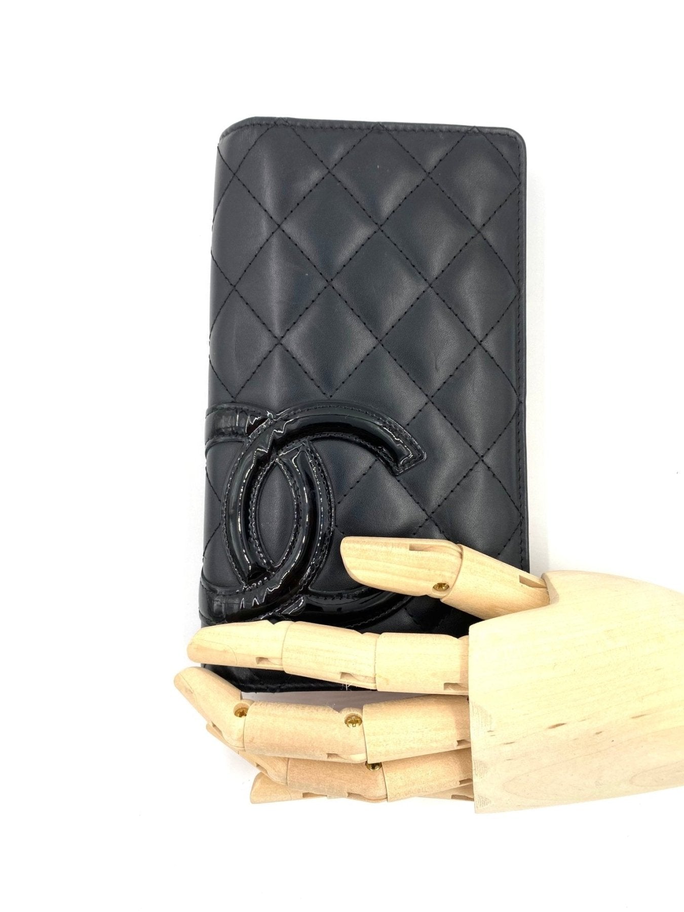 CHANEL Portemonnaie CC schwarzes Lammleder mit gestepptem Muster und CC-Logo, elegant prasentiert auf Holzhand