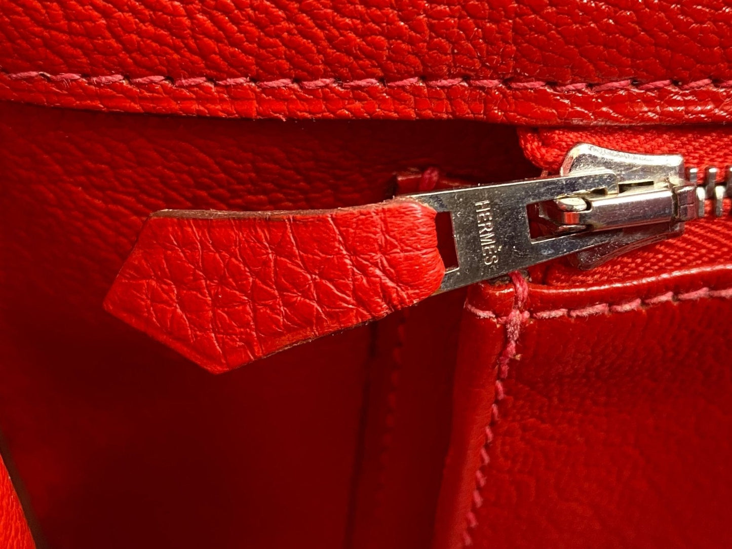 Nahaufnahme eines Reissverschlussdetails der HERMES Birkin 35 Tasche in leuchtendem Capucine-Rot aus Clemence Leder