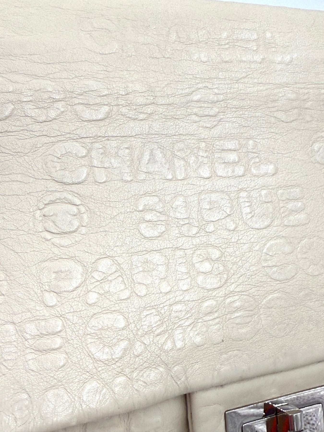 CHANEL Double Flap Bag Jumbo in creme, Detailaufnahme des strukturierten Kalbsleders mit gepraegtem Markenschriftzug