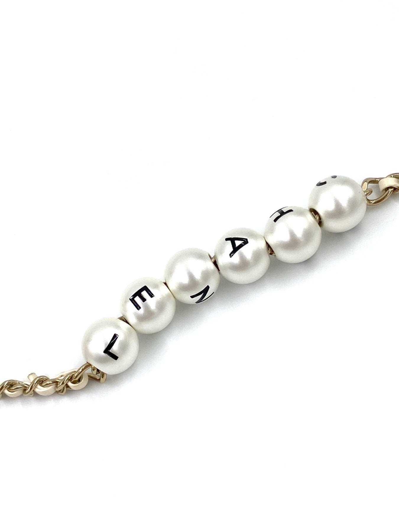 CHANEL Classic Flap Mini Pearls ivory: Goldene Kette mit weissen Perlen und schwarzen Buchstaben auf Perlenkette