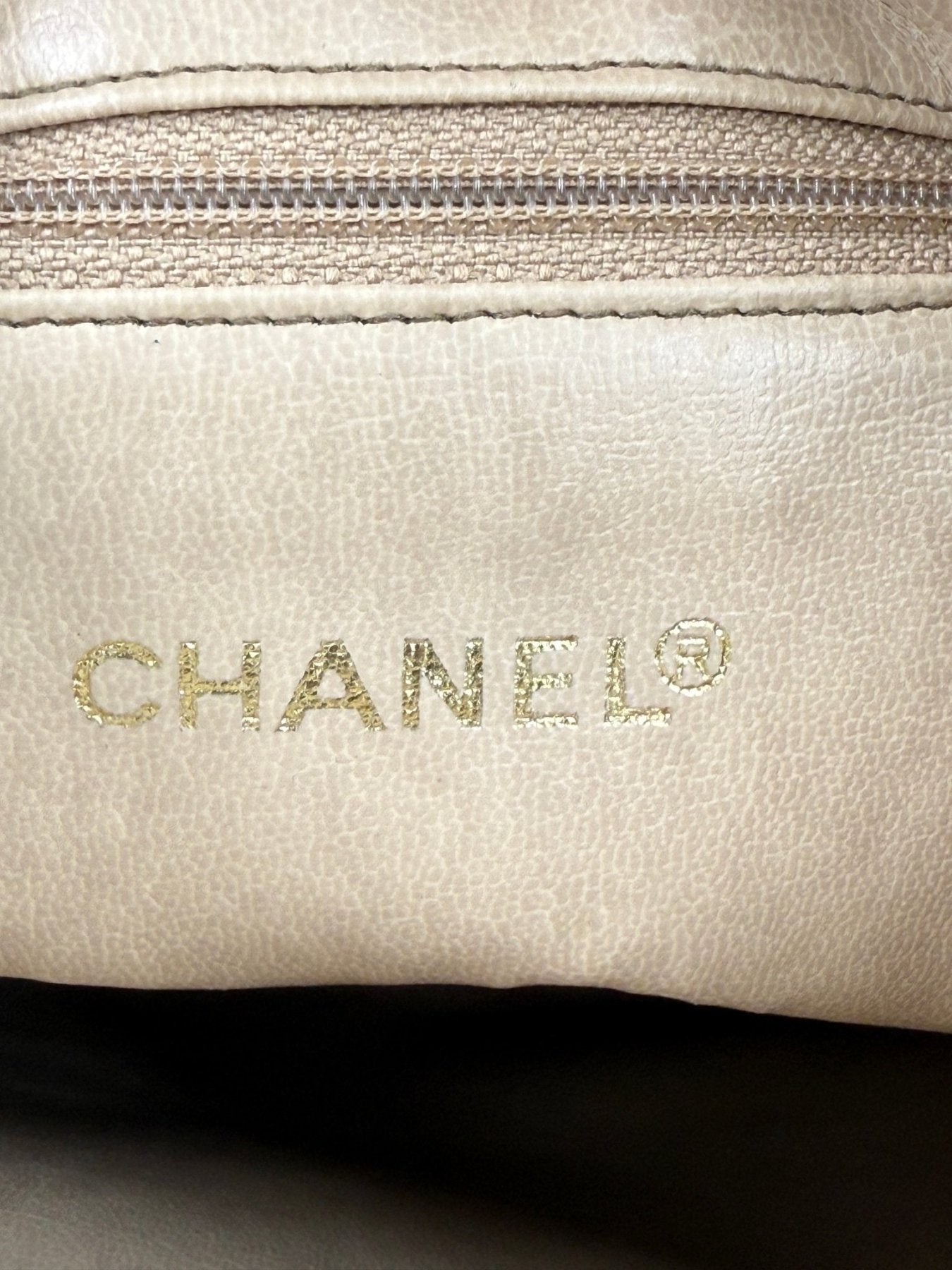 CHANEL Shopper creme GHW Detailaufnahme des goldenen Logos auf cremefarbenem Leder mit Reissverschlussdetail