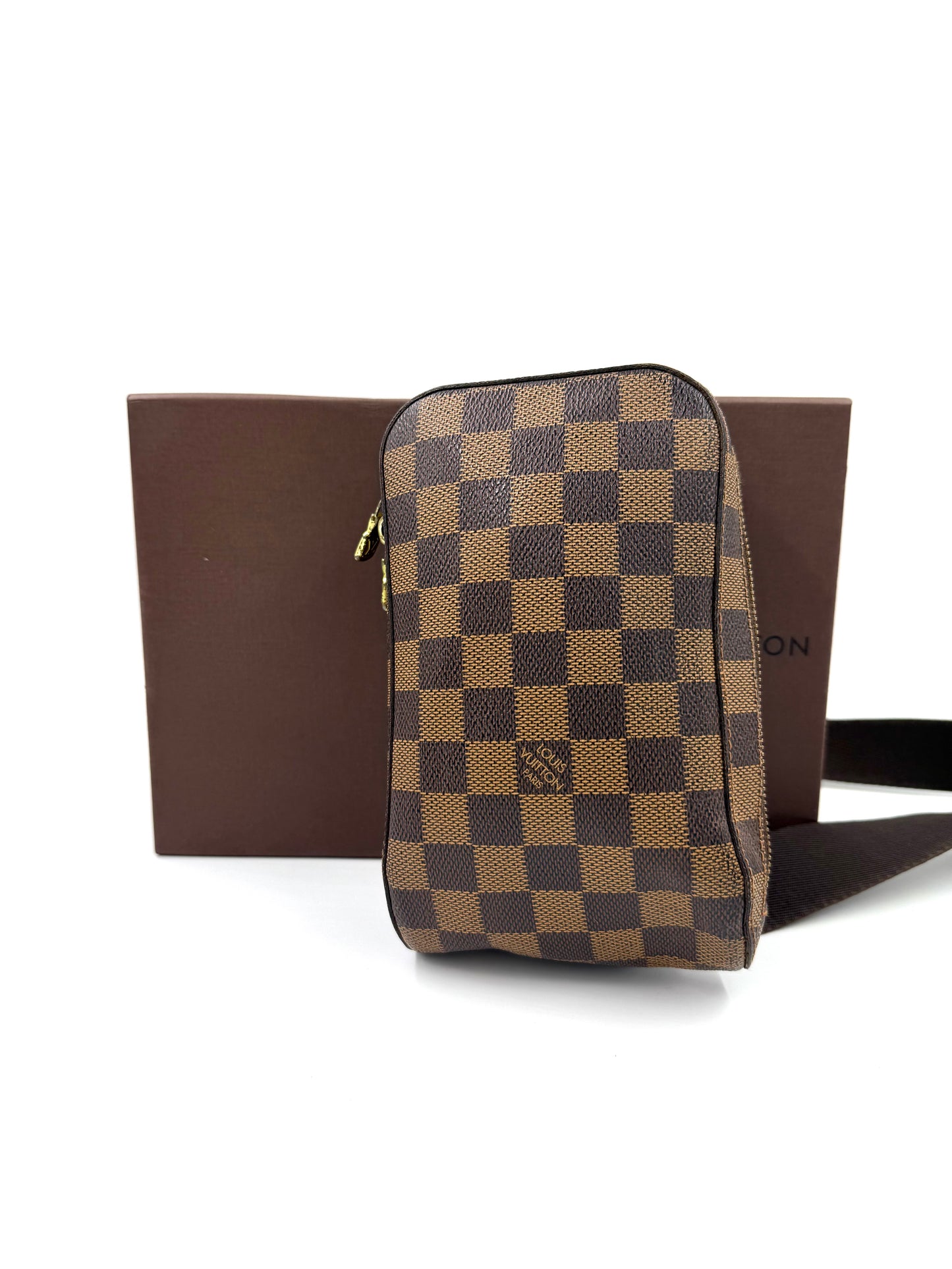 Louis Vuitton Geronimos Damier Ebene Tasche aus Canvas mit klassischem Schachbrettmuster vor braunem Hintergrund