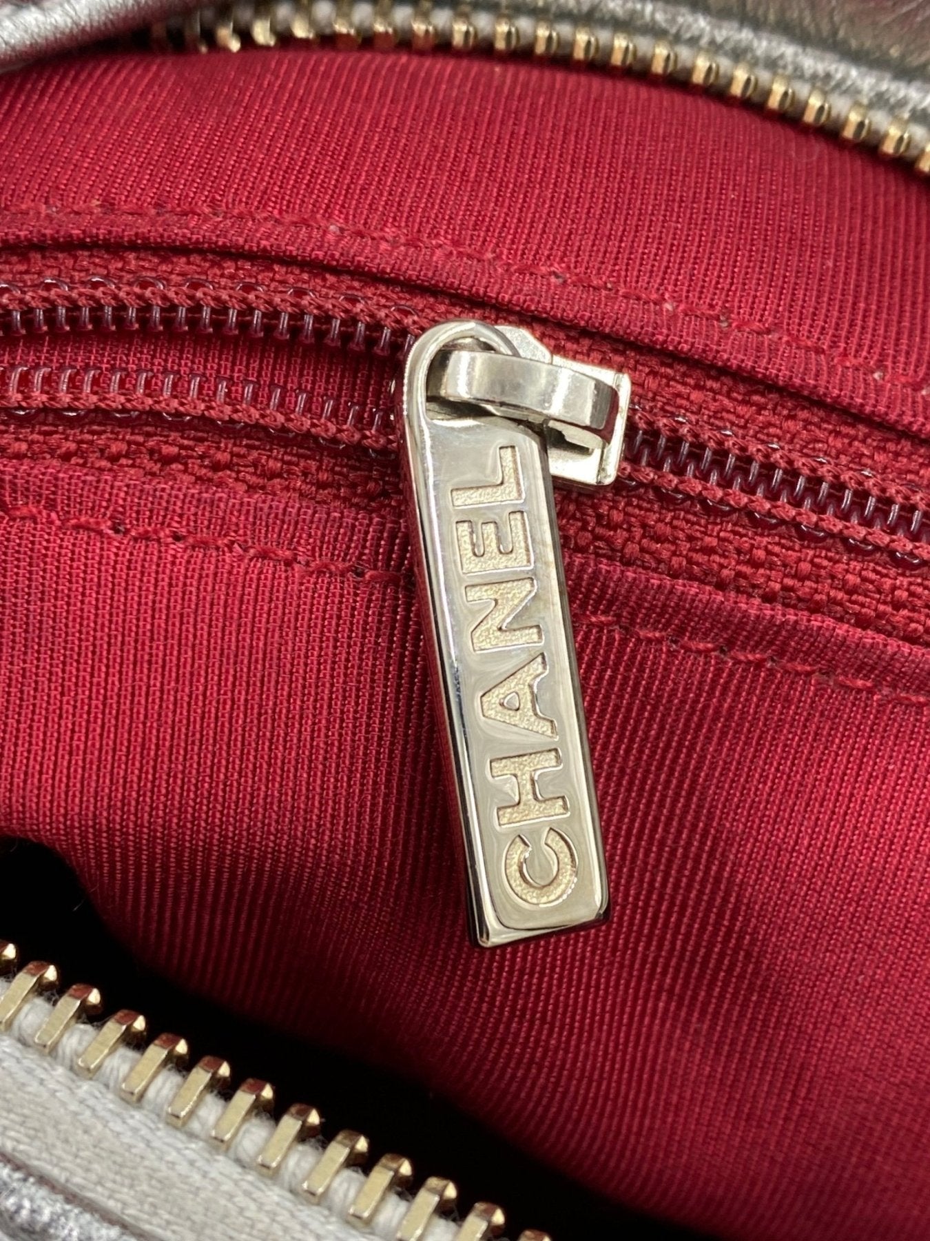 CHANEL Gabrielle Tasche Detail: Silberner Reissverschluss mit CHANEL Schriftzug auf rotem Innenfutter