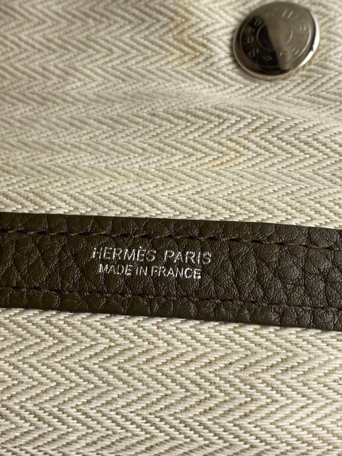 Nahaufnahme des HERMES PARIS Markenstempels auf Togoleder mit Textilinnenfutter und Palladiumknopf der Garden Party 36