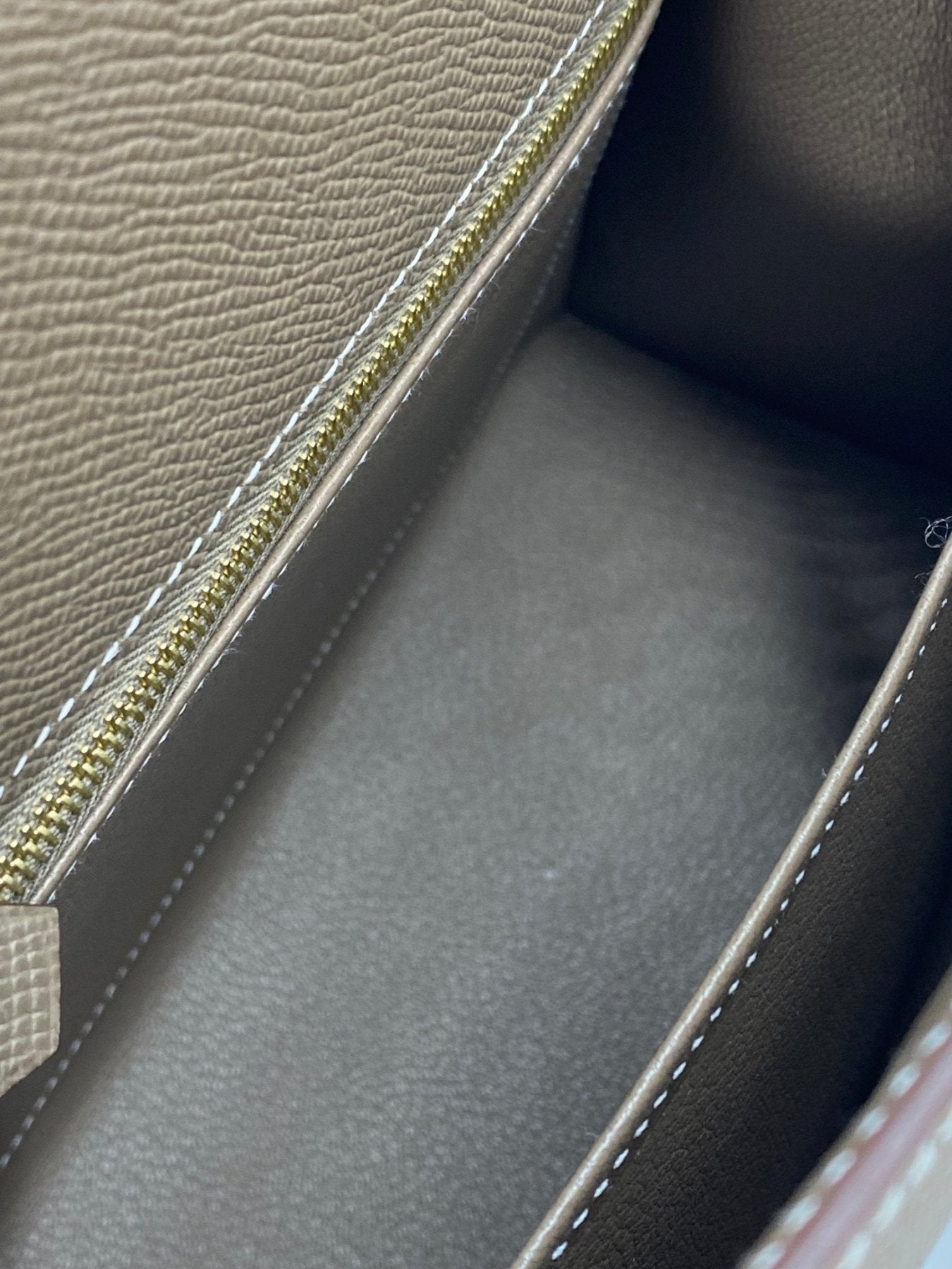 Detailaufnahme des Innenraums der HERMES Kelly 25 Epsom Sellier in Etoupe mit goldener Reissverschlussleiste und Ledertextur
