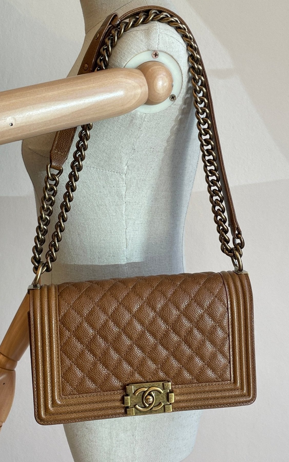 CHANEL Boy Bag Medium Caviar in cognacfarbenem Leder mit gestepptem Muster und Metallkette auf Schneiderpuppe