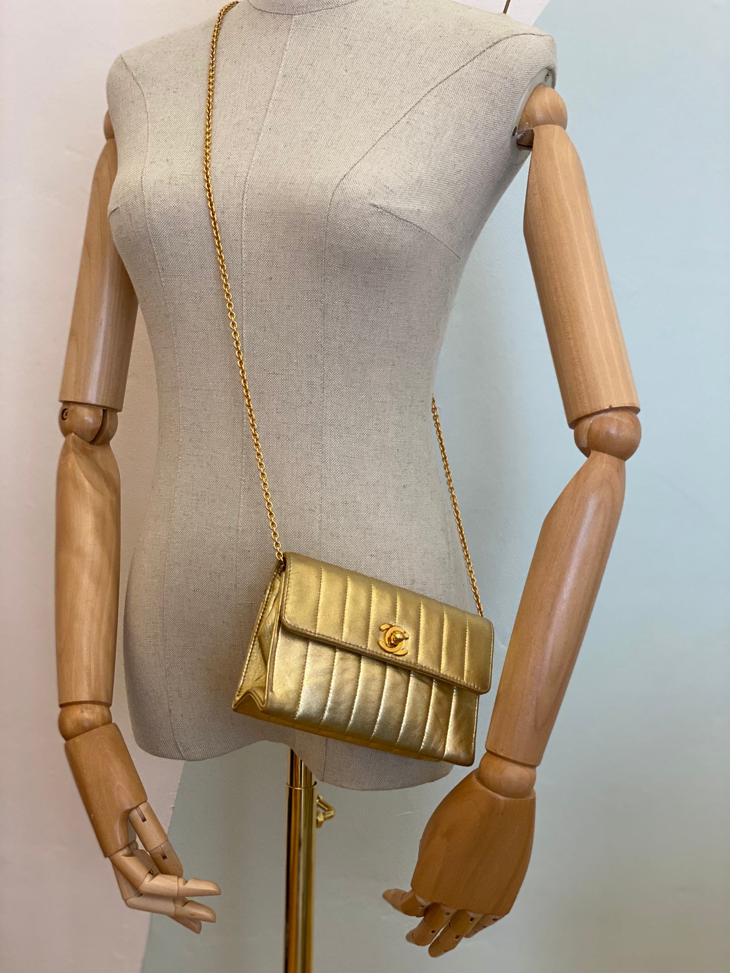 CHANEL Clutch Mademoiselle gold Vintage Mini Tasche aus Leder mit 24K vergoldeter Hardware, elegante Abendtasche, getragen an Schaufensterpuppe.