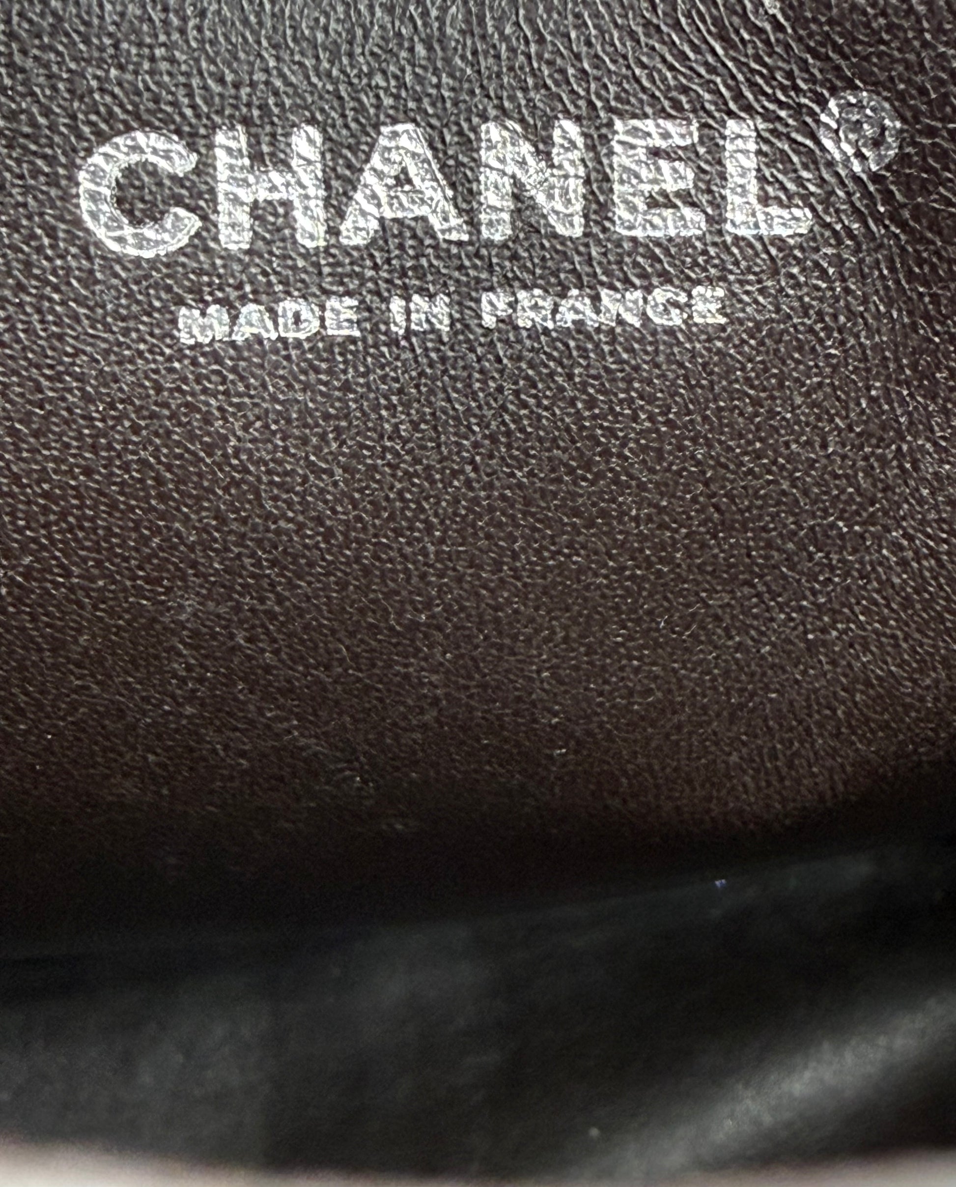 CHANEL Timeless Single Flap Jumbo Caviar dunkelbraun SHW Logo mit Prägung "Made in France" auf Lederoberfläche.
