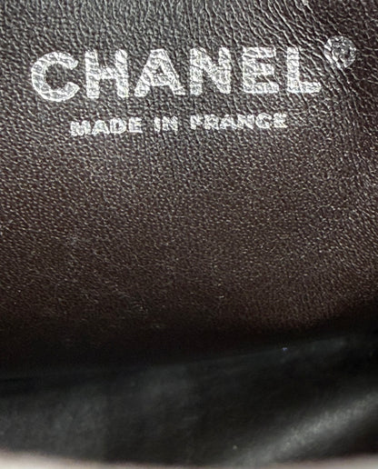 CHANEL Timeless Single Flap Jumbo Caviar dunkelbraun SHW Logo mit Prägung "Made in France" auf Lederoberfläche.