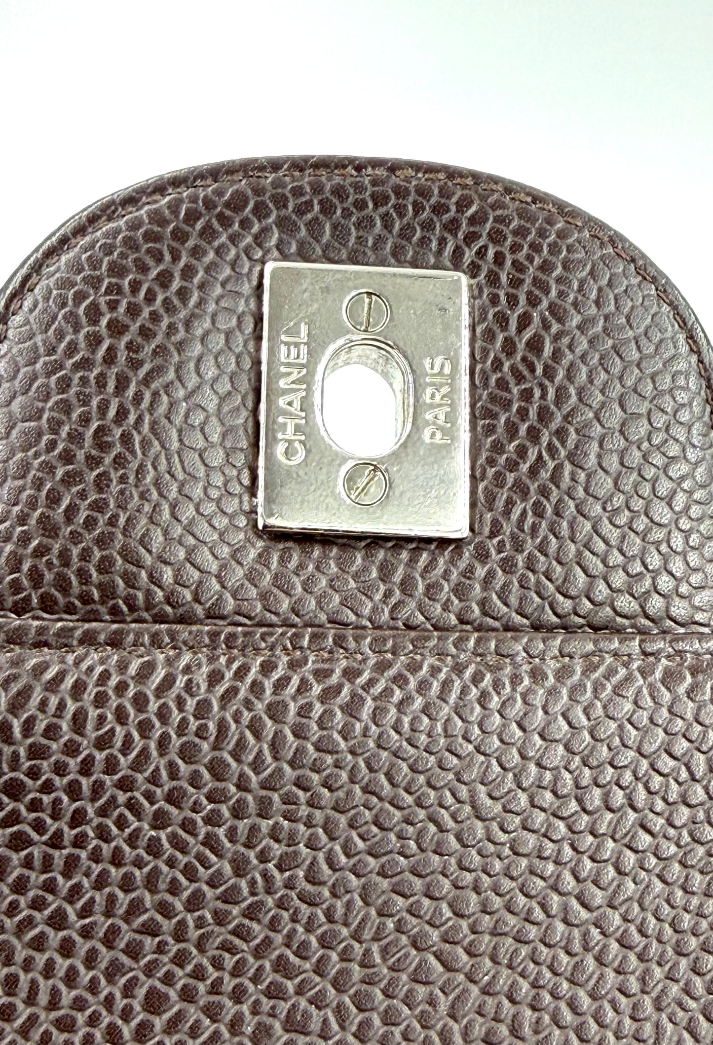 Detailaufnahme des Verschlusses der CHANEL Timeless Single Flap Jumbo Caviar dunkelbraun SHW Luxus-Handtasche