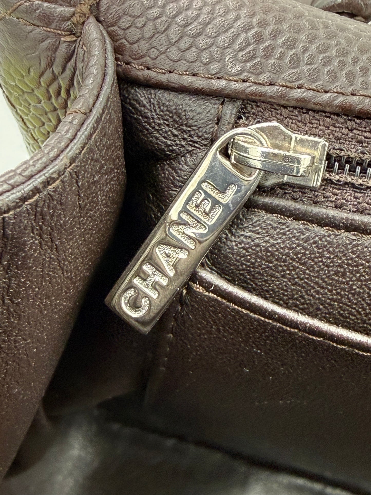 Detailansicht des Reißverschlussanhängers der CHANEL Timeless Single Flap Jumbo Caviar dunkelbraun SHW Tasche.