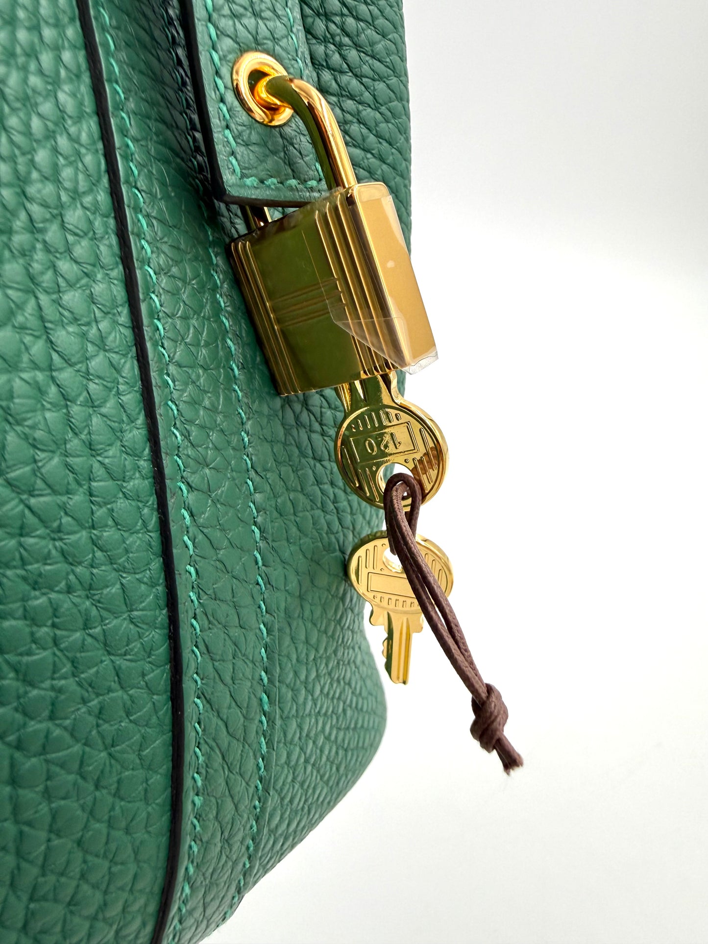 Nahaufnahme von grünem HERMÈS Picotin 18 Lock Clemence Vert Moyen mit goldenem Schloss und Schlüsseln aus Leder.