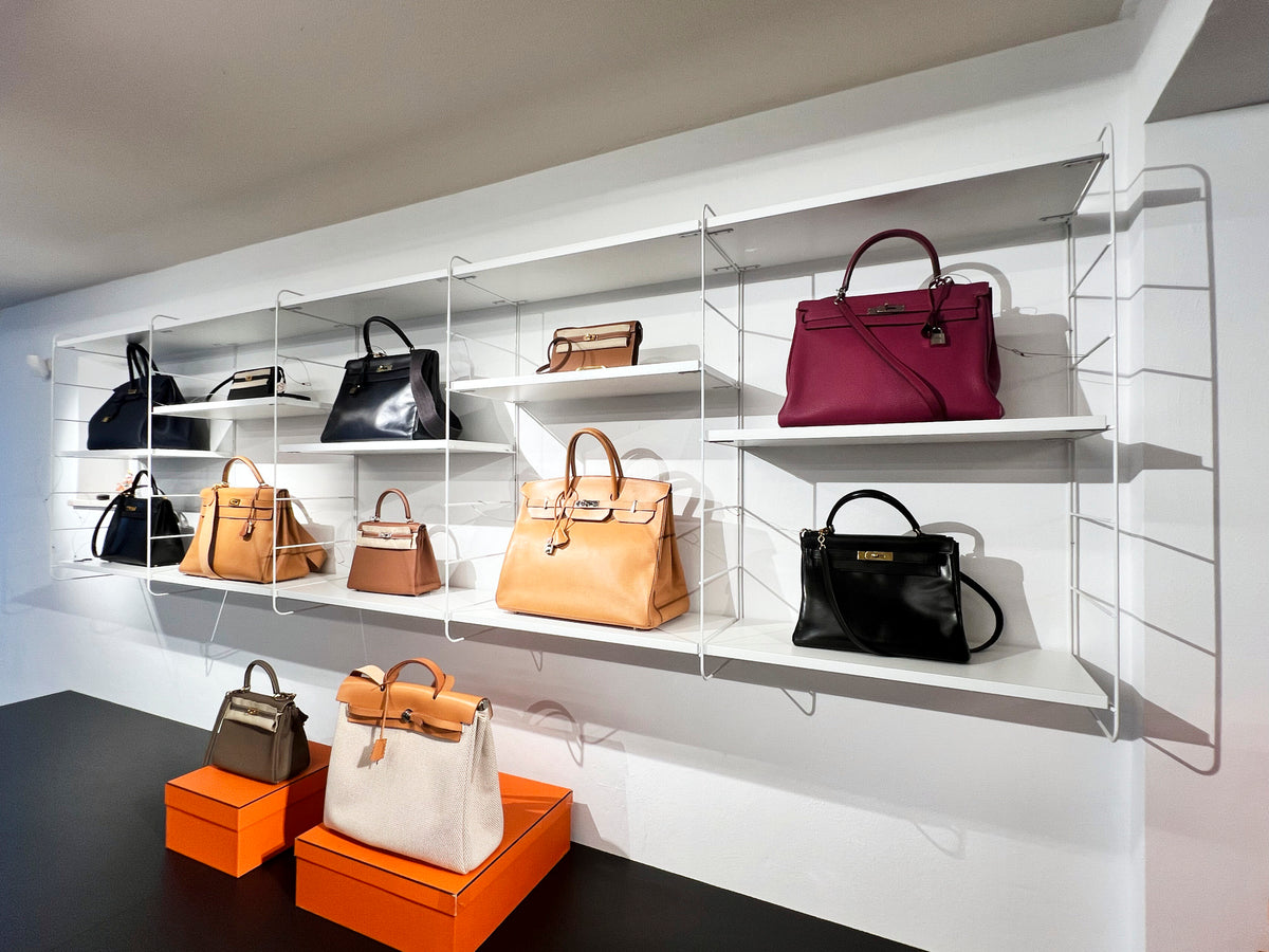 Verschiedene Designerhandtaschen auf weißen Wandregalen in einer stilvollen Boutique ausgestellt