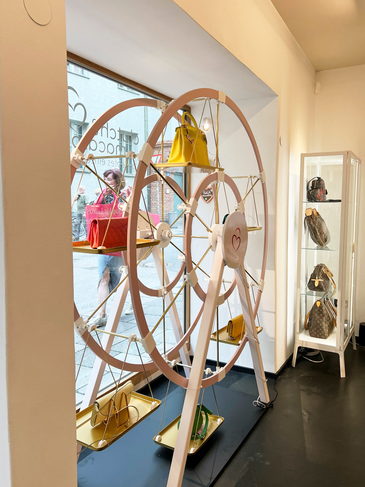 Handtaschen auf einem dekorativen Radständer und in einer Glasvitrine einer stilvollen Boutique ausgestellt