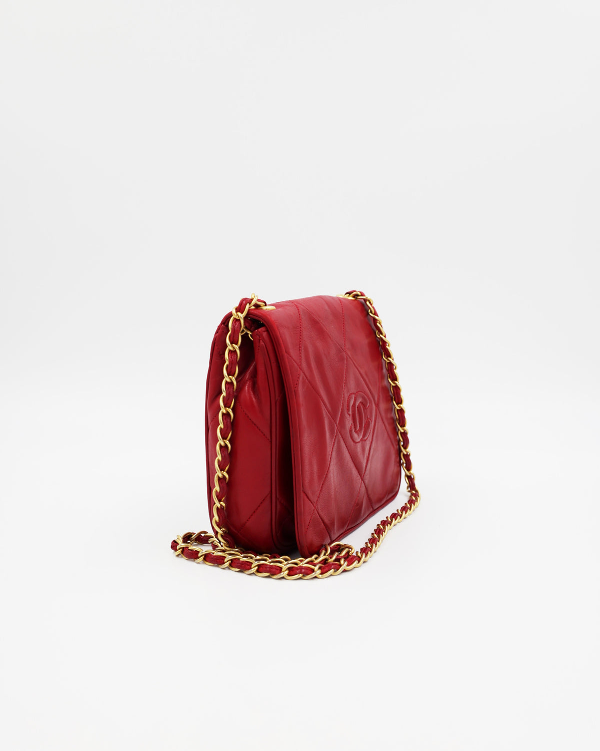 Rote gesteppte Designerhandtasche mit goldener Kette vor weißem Hintergrund