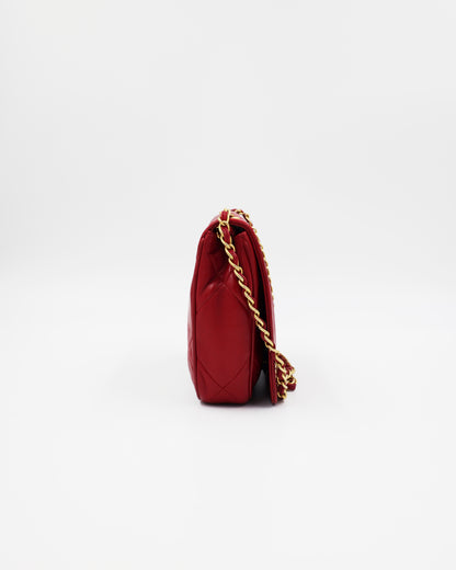 Rote gesteppte Handtasche mit goldfarbener Kette auf weißem Hintergrund