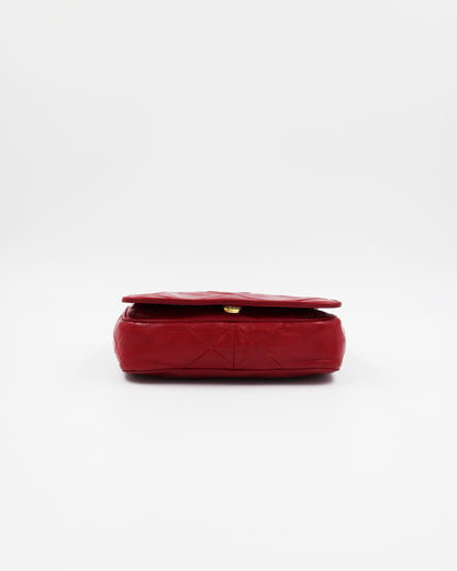 Rote gesteppte Clutch mit goldfarbenem Verschluss auf weißem Hintergrund
