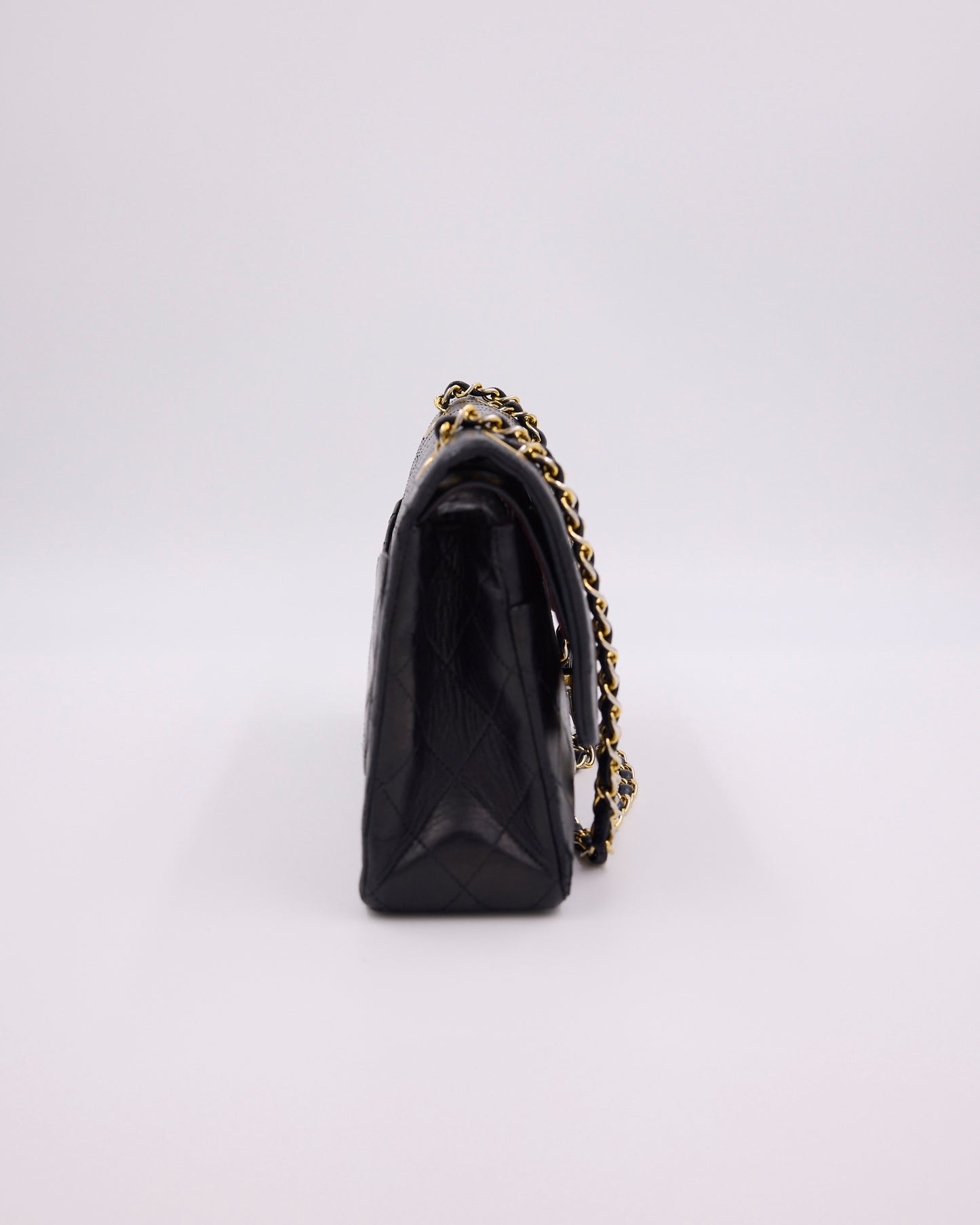 Schwarze gesteppte Handtasche mit goldfarbener Kette in Seitenansicht