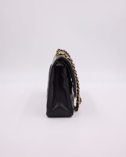 Schwarze gesteppte Handtasche mit goldfarbener Kette in Seitenansicht