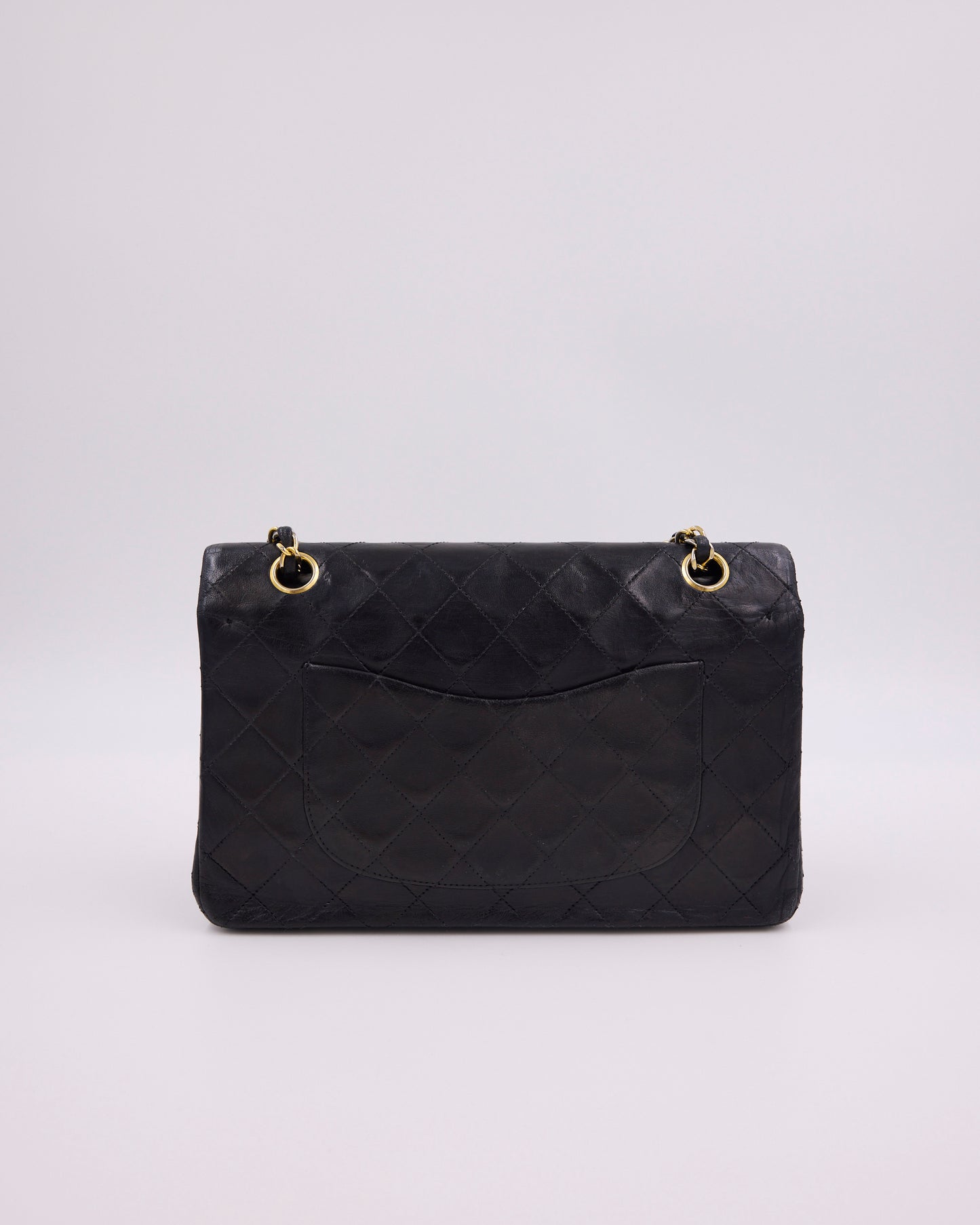 Schwarze gesteppte Designerhandtasche mit goldfarbenen Kettendetails vor hellem Hintergrund