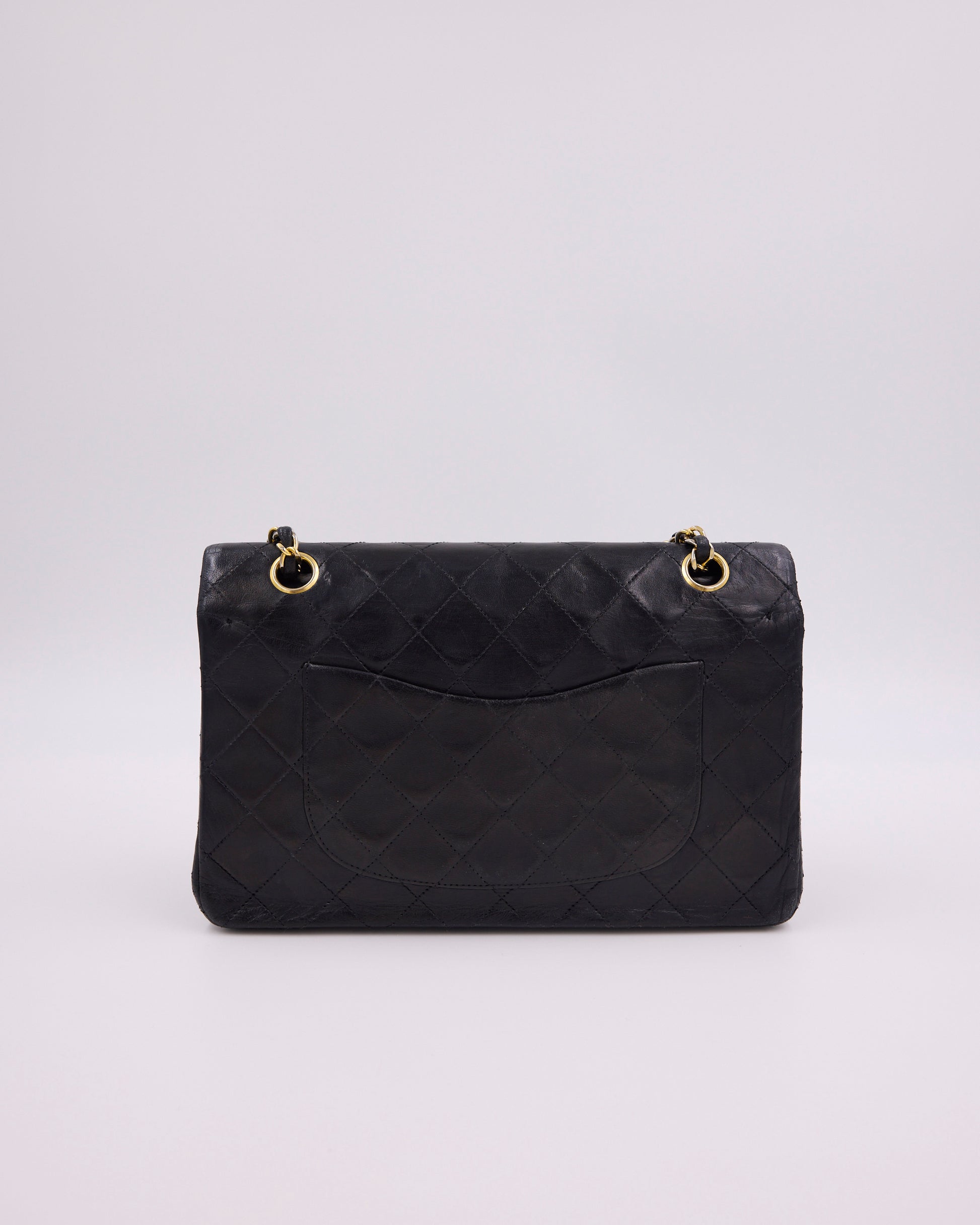 Schwarze gesteppte Designerhandtasche mit goldfarbenen Kettendetails vor hellem Hintergrund