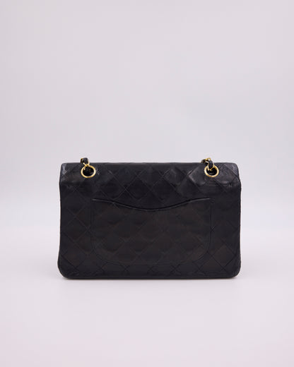 Schwarze gesteppte Designerhandtasche mit goldfarbenen Kettendetails vor hellem Hintergrund