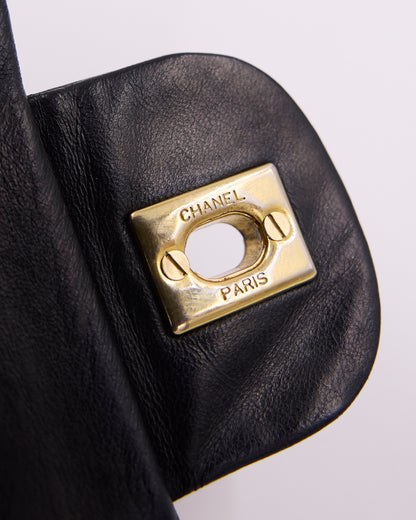 Nahaufnahme einer schwarzen Ledertasche mit goldfarbenem CHANEL PARIS Verschluss