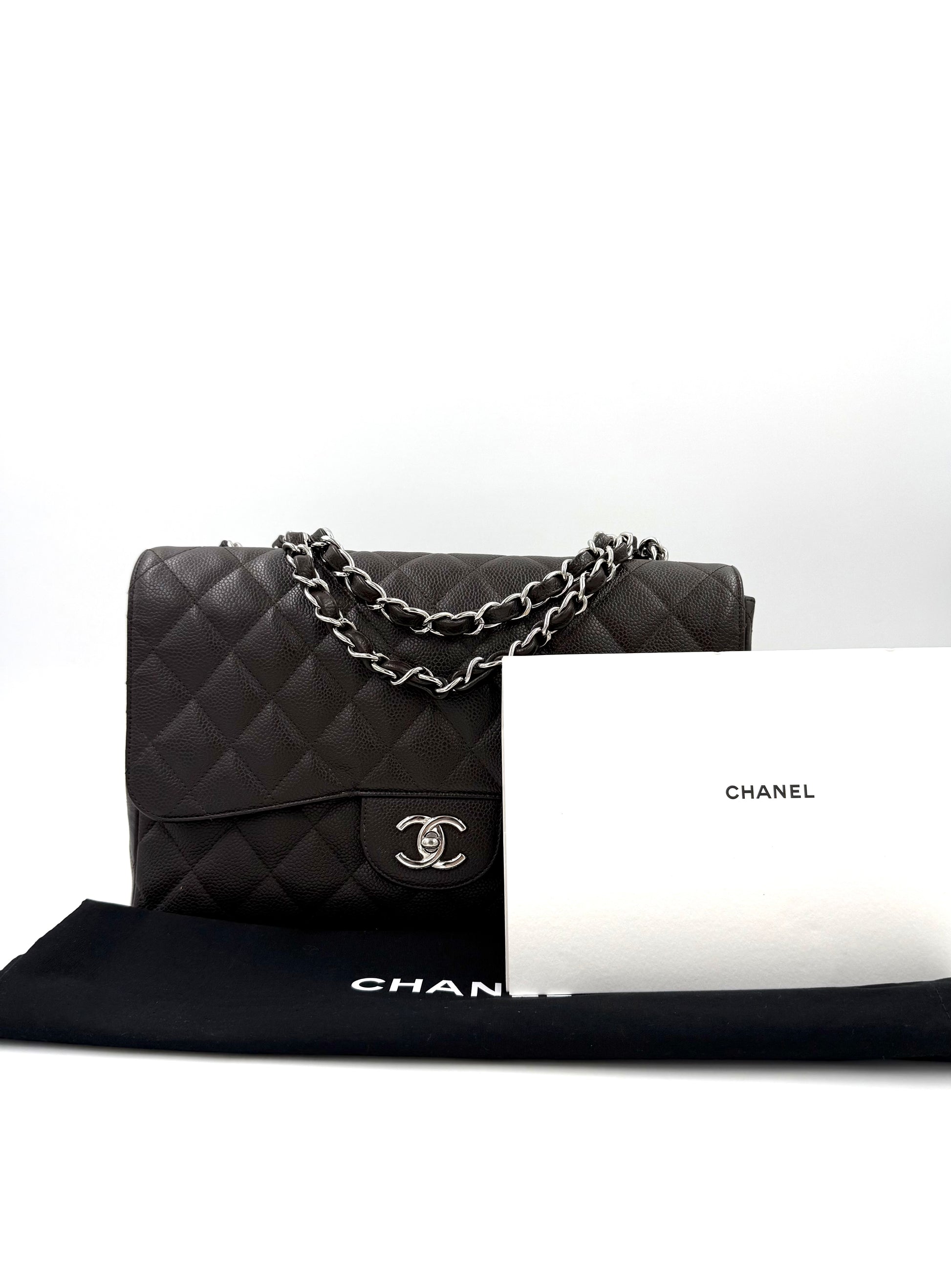 CHANEL Timeless Single Flap Jumbo Caviar dunkelbraun SHW Handtasche mit Kettenriemen und Staubbeutel vor weißem Hintergrund